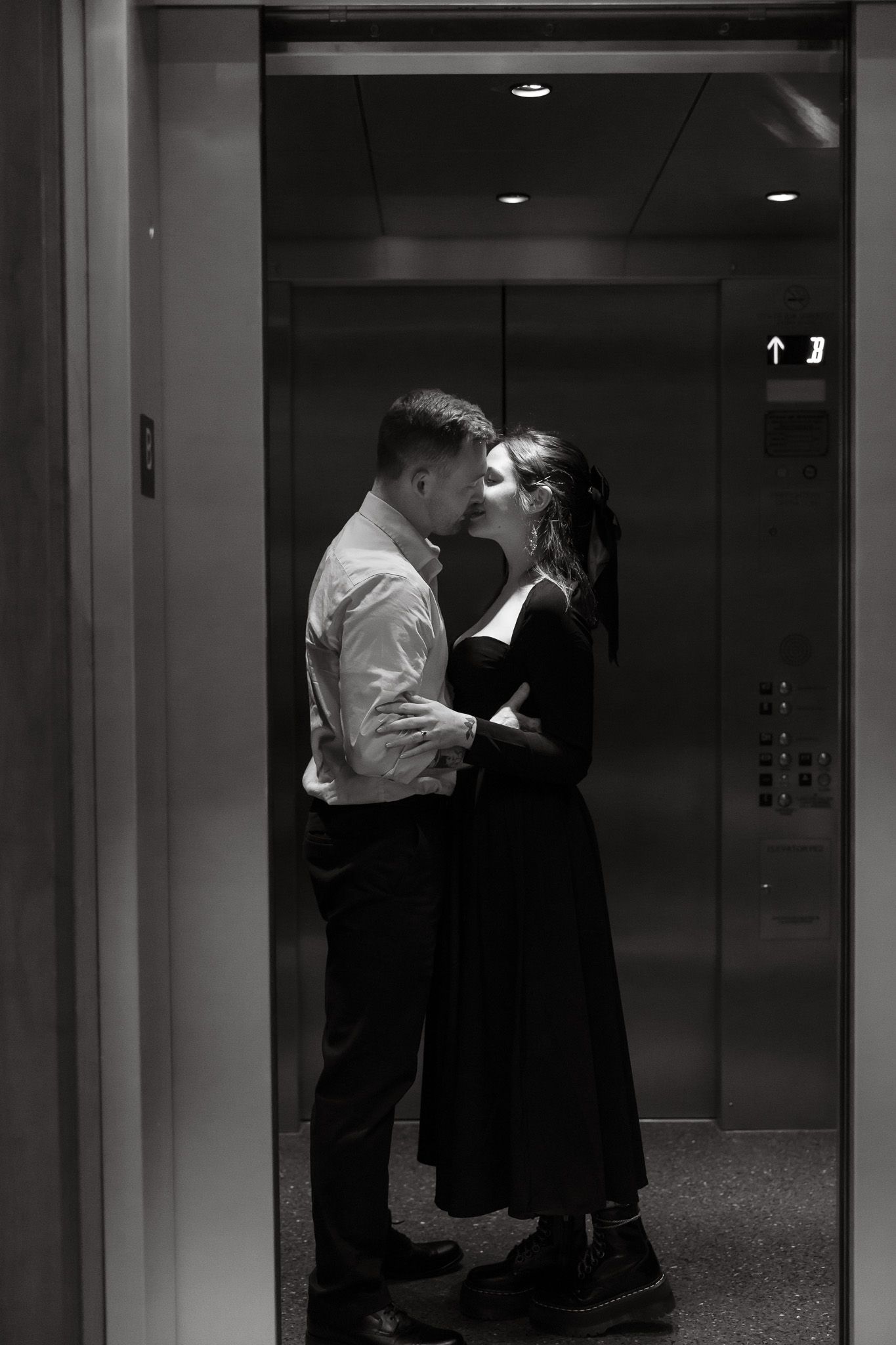 Black and white photo of a romantic couple sharing an intimate moment while embracing in an elevator.