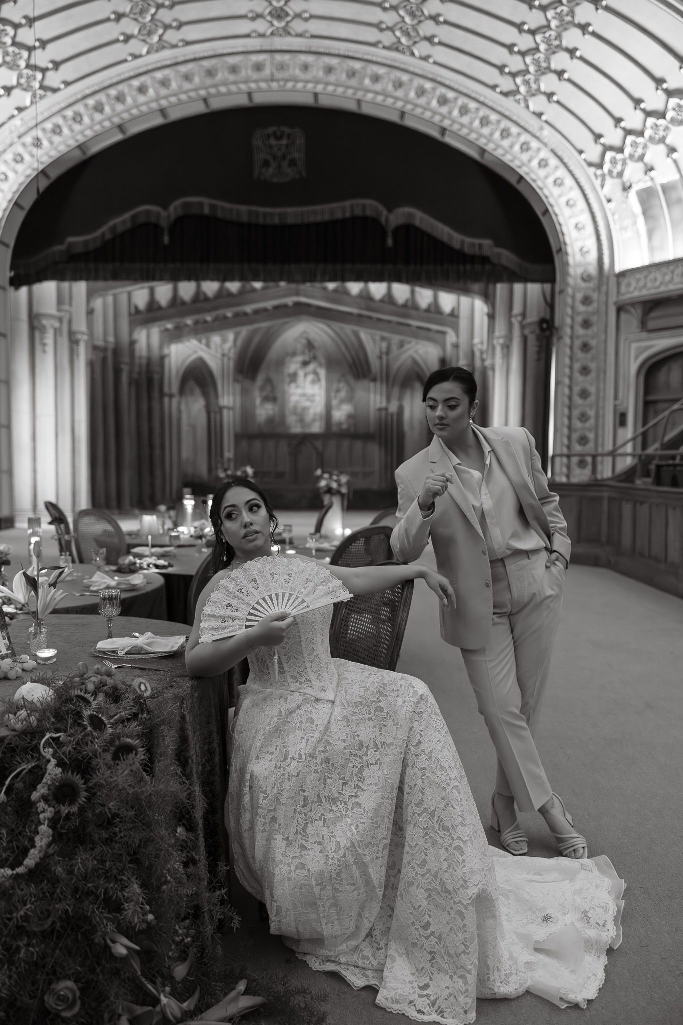 A series of four black and white photos showing a bride in an elegant lace gown posing with a decorative fan in an ornate venue.