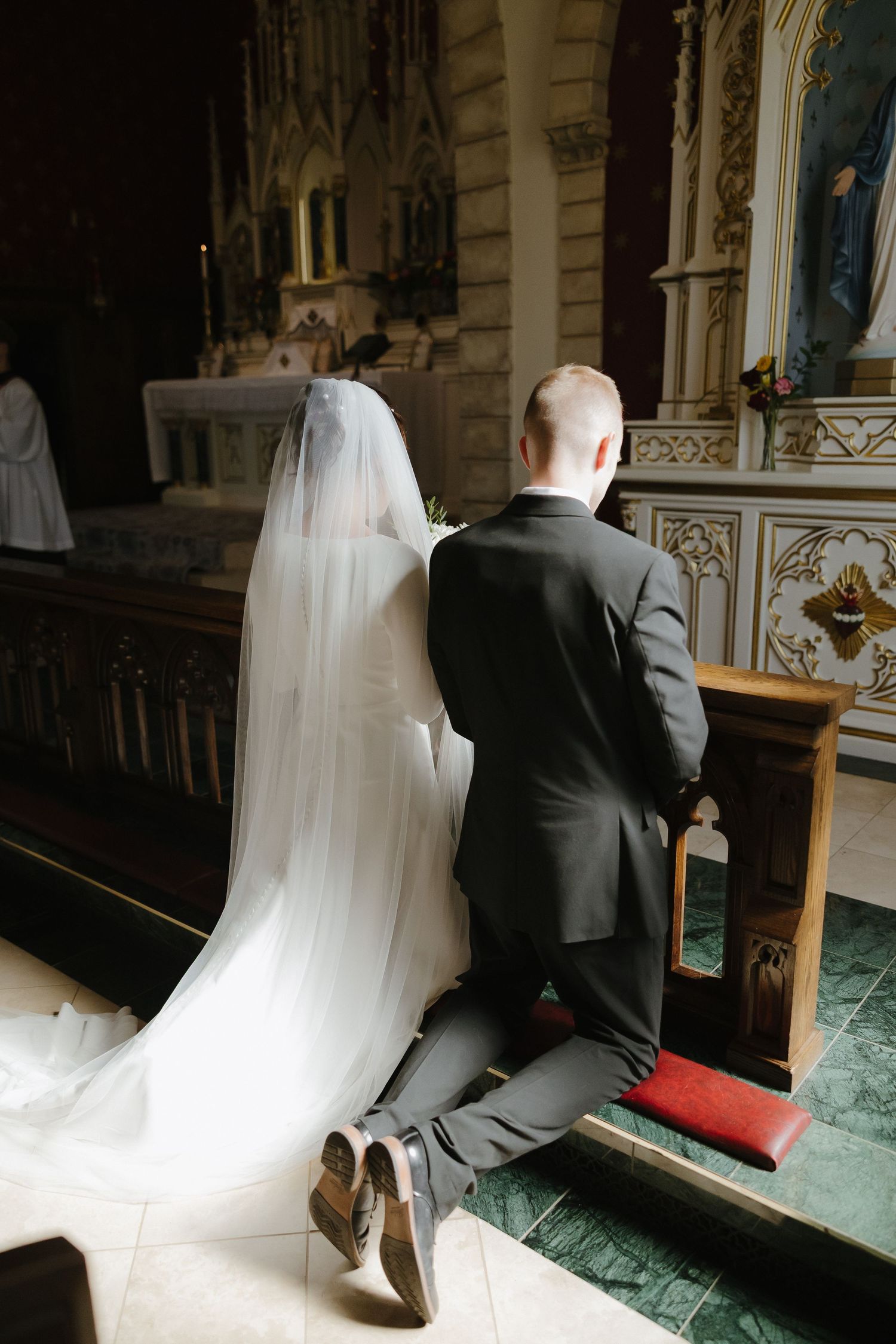 Couple kneeling in prayer at church pews.