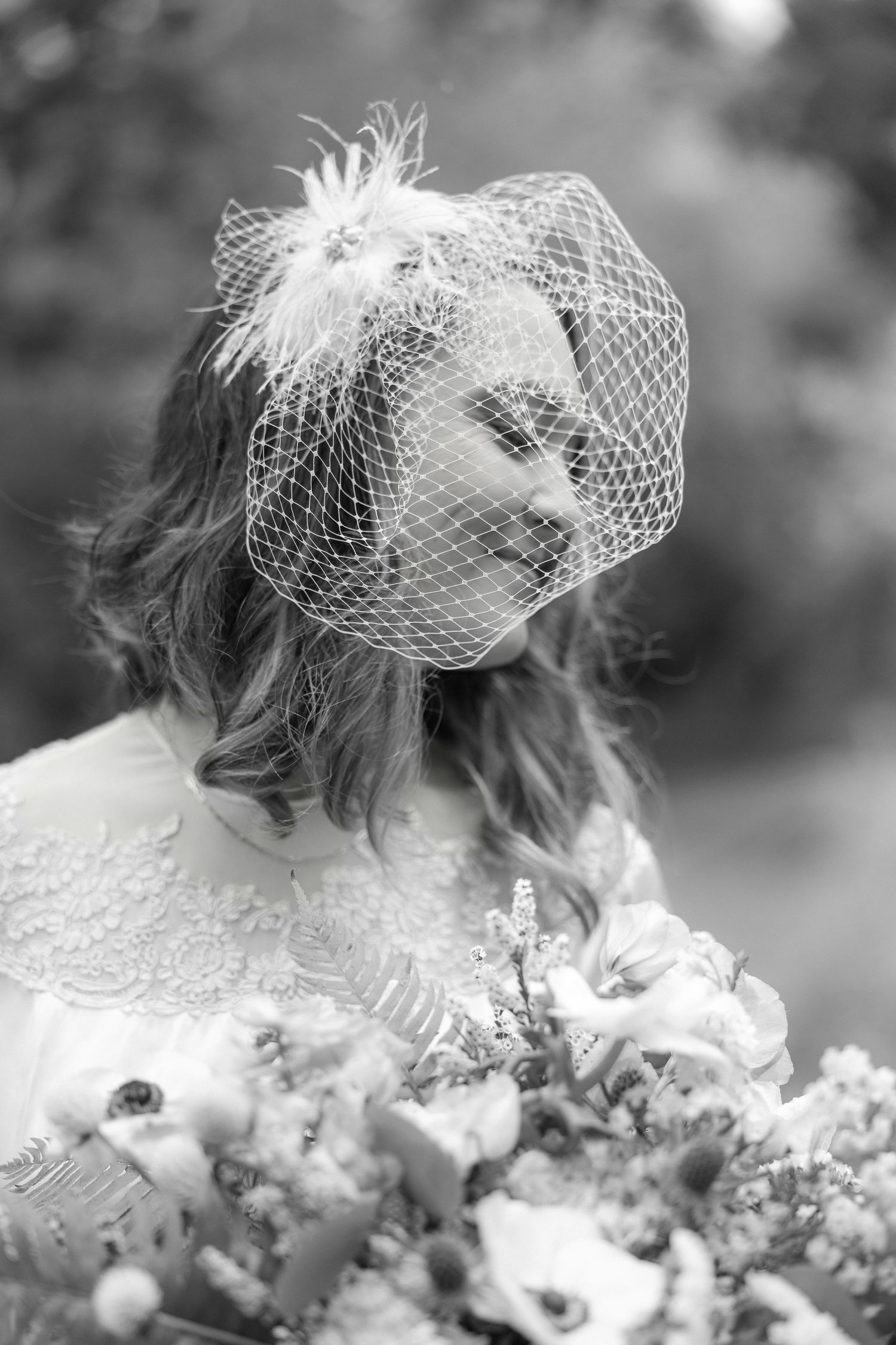 Black and white close-up of bridal veil and bouquet with delicate flowers.