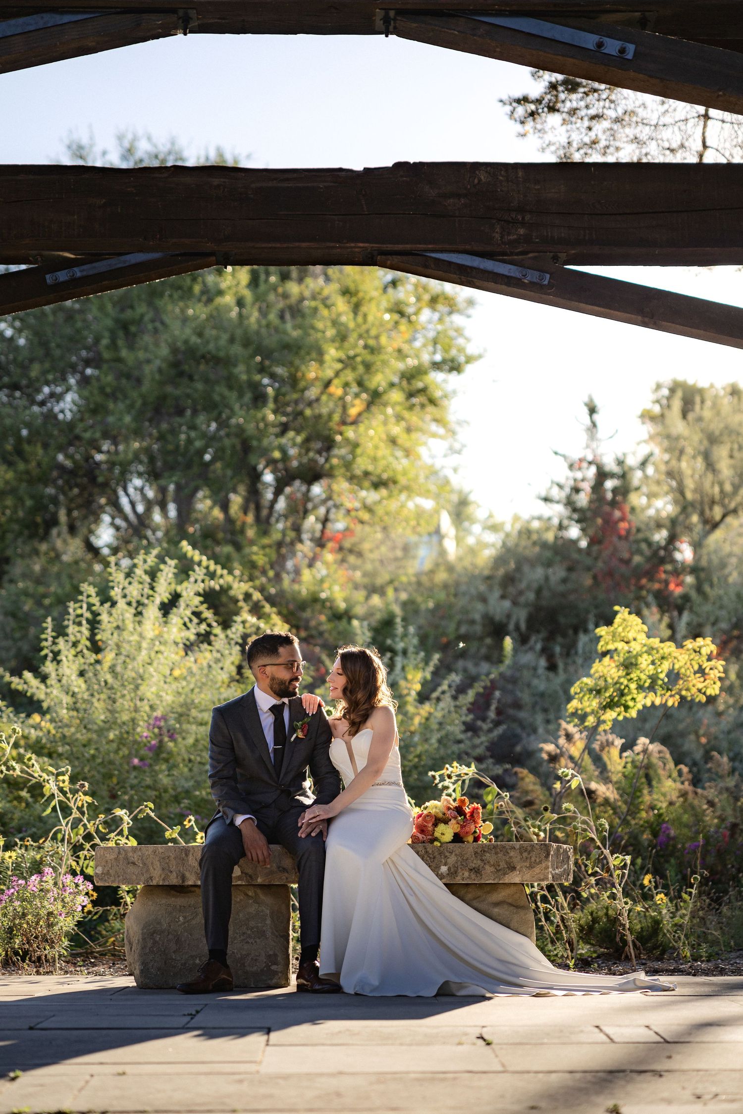 Romantic wedding photos taken at sunset under wooden pergola.