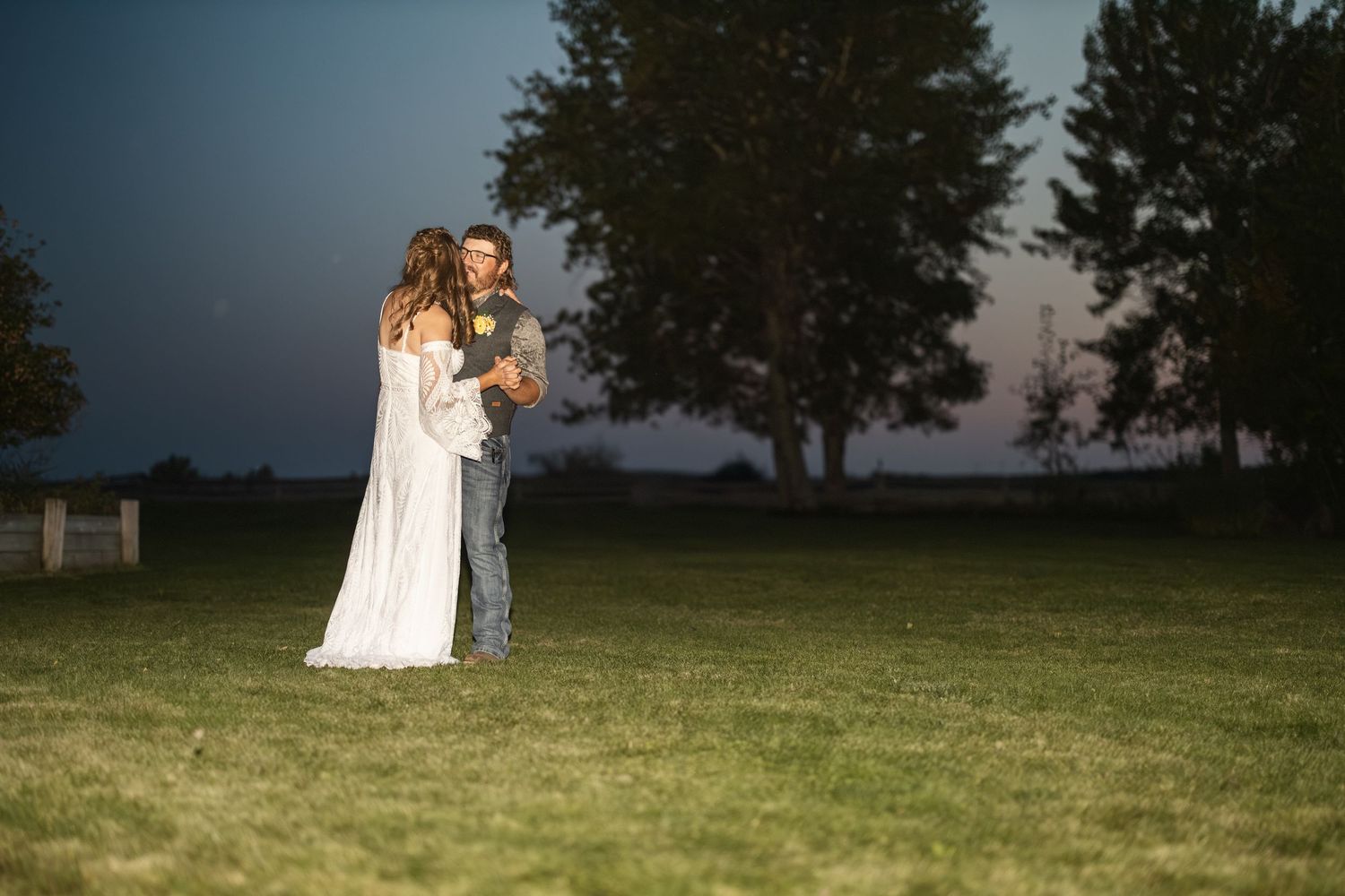 A couple shares an intimate moment in an outdoor garden setting at dusk.