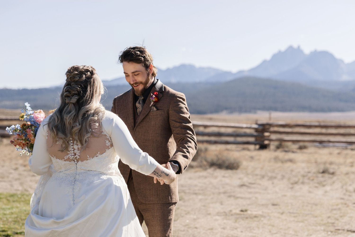A couple walks together across a scenic desert landscape with mountains in the distance.