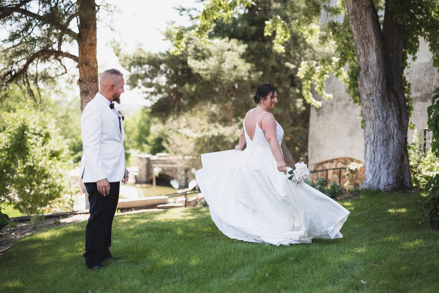 Candid wedding moment captured as bride twirls her dress in a garden setting.