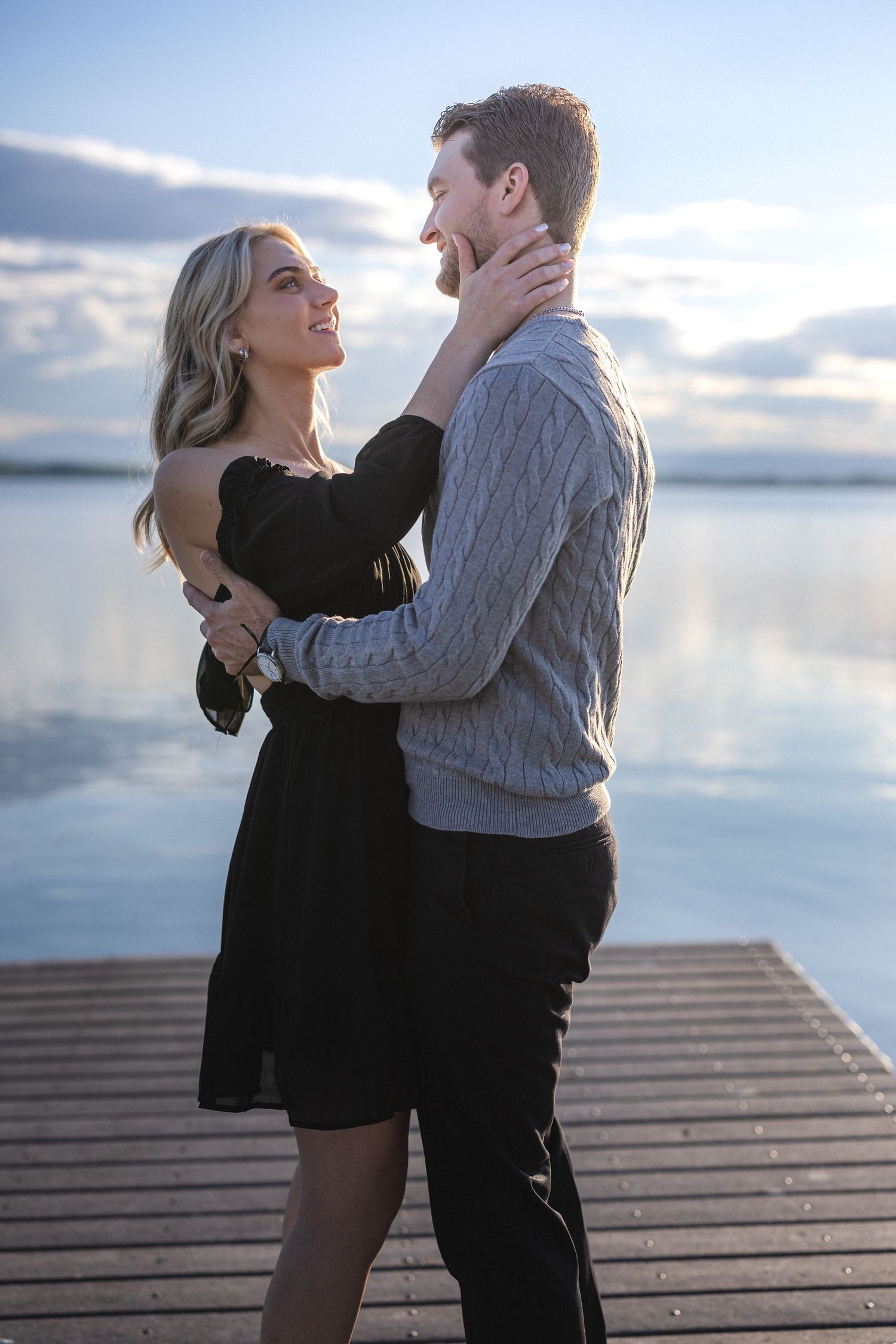 A couple sharing an intimate moment on a dock by a serene lake.