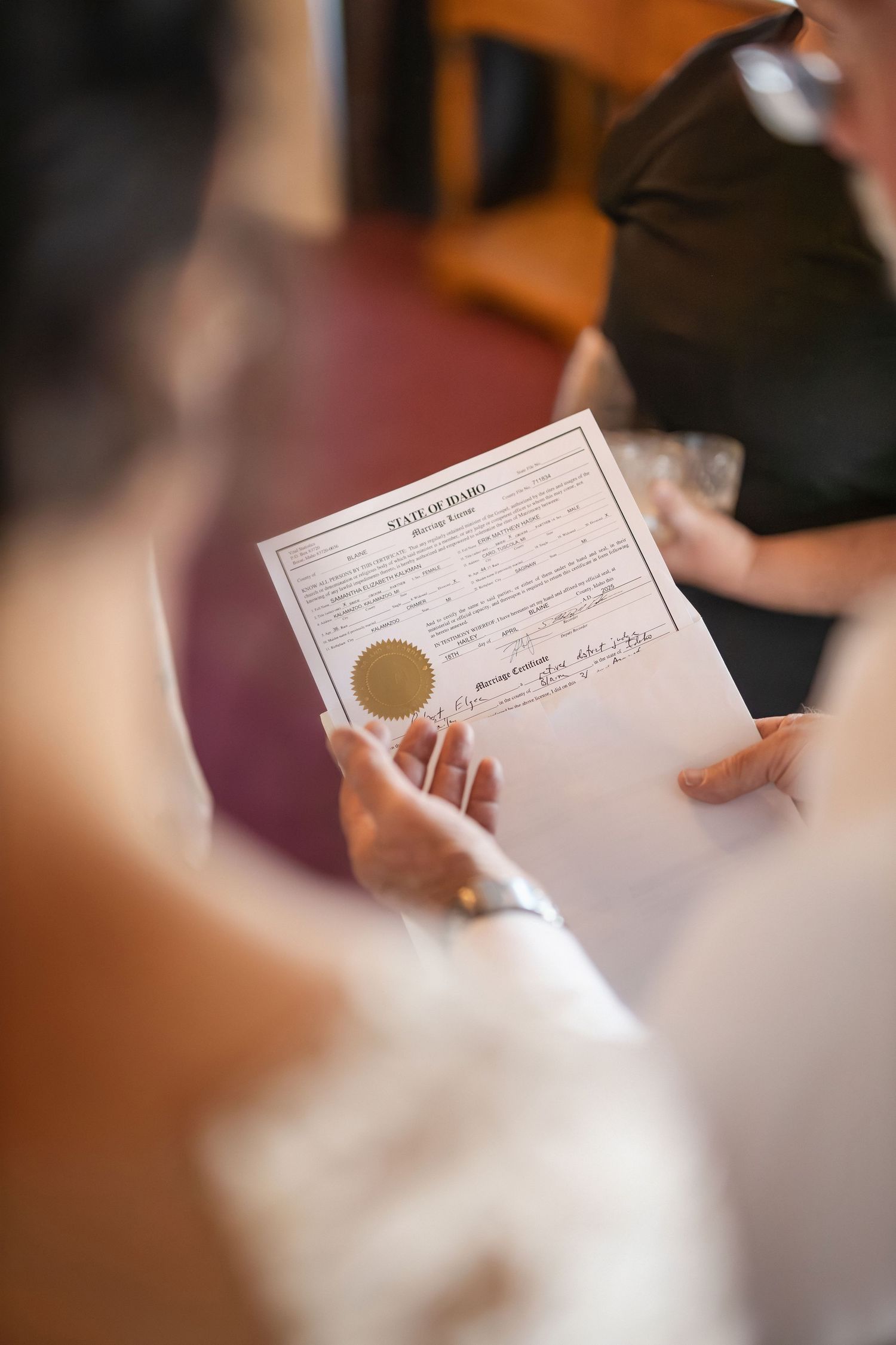 A close-up shot of hands holding a wedding certificate during the ceremony.