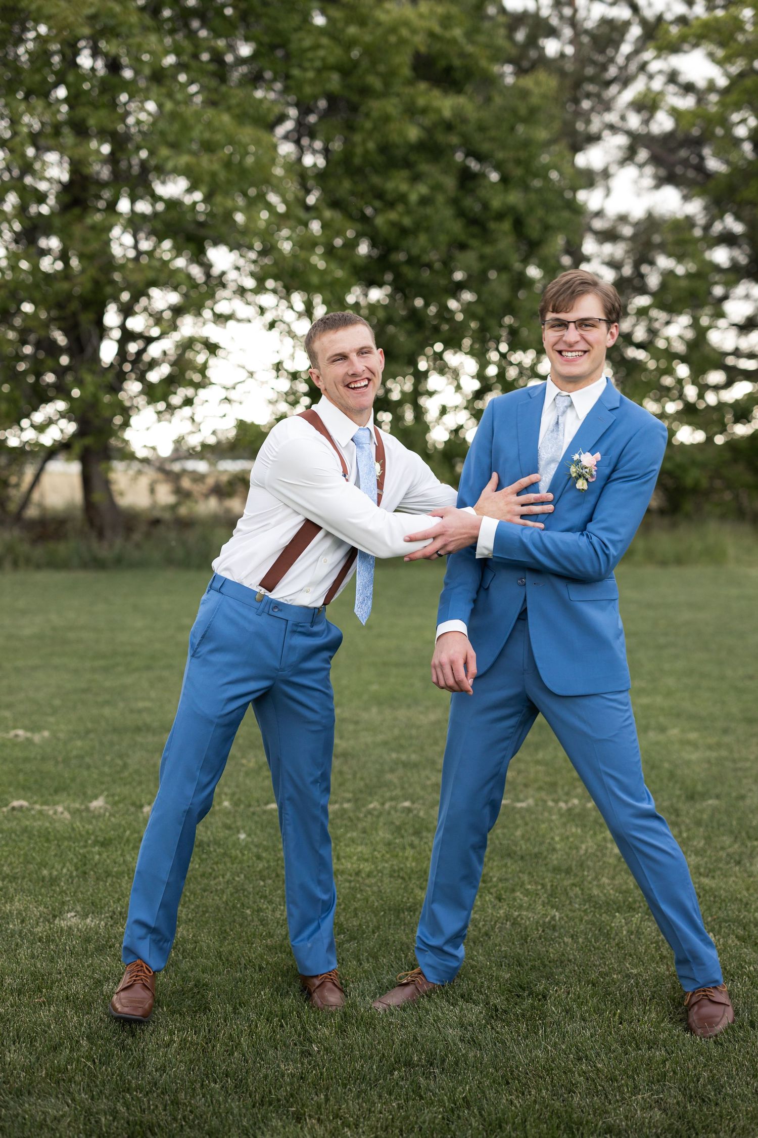 Groomsmen in bright blue suits sharing a playful moment on the lawn.