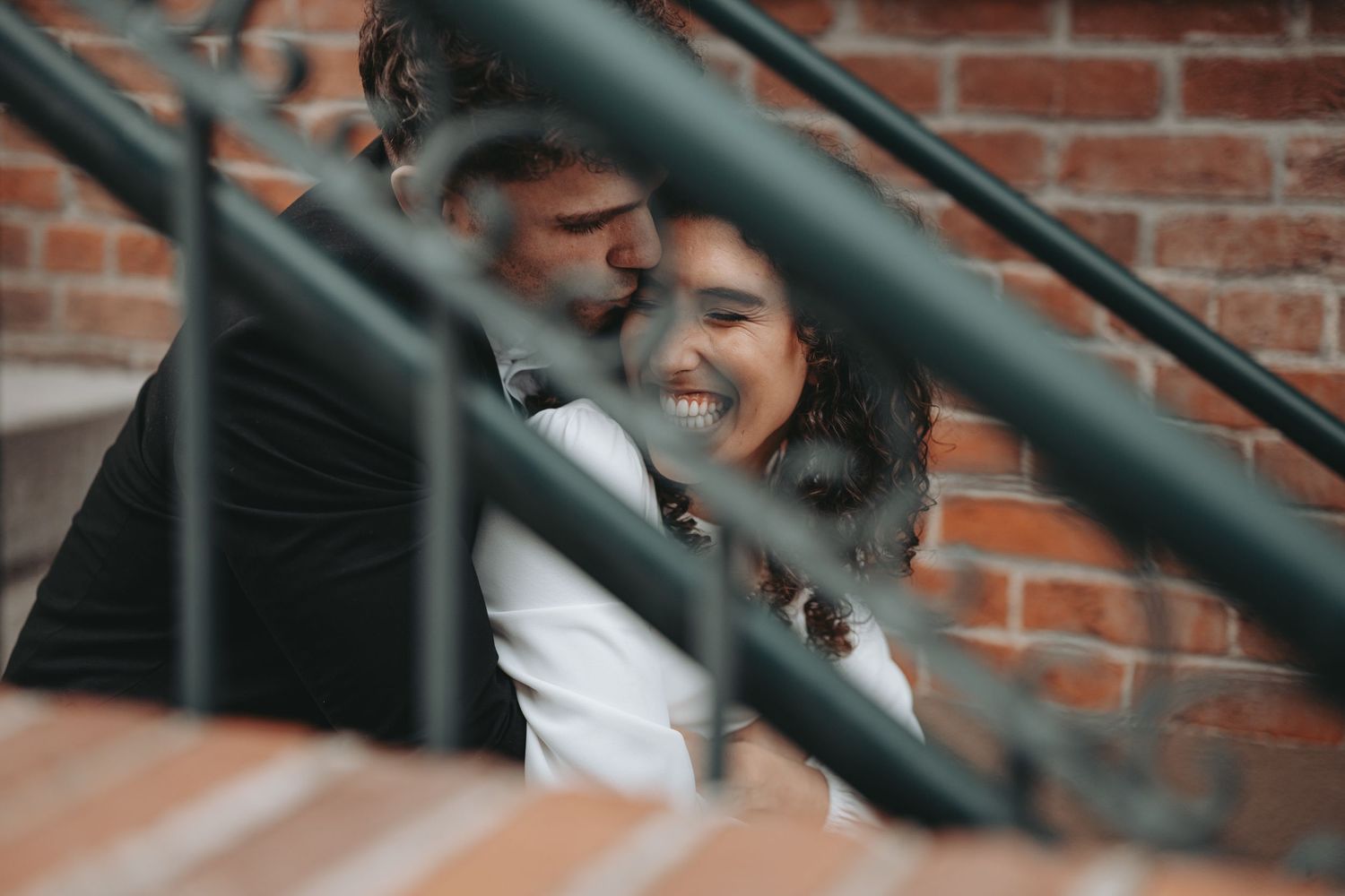 A romantic moment captured through metal railings on urban steps.