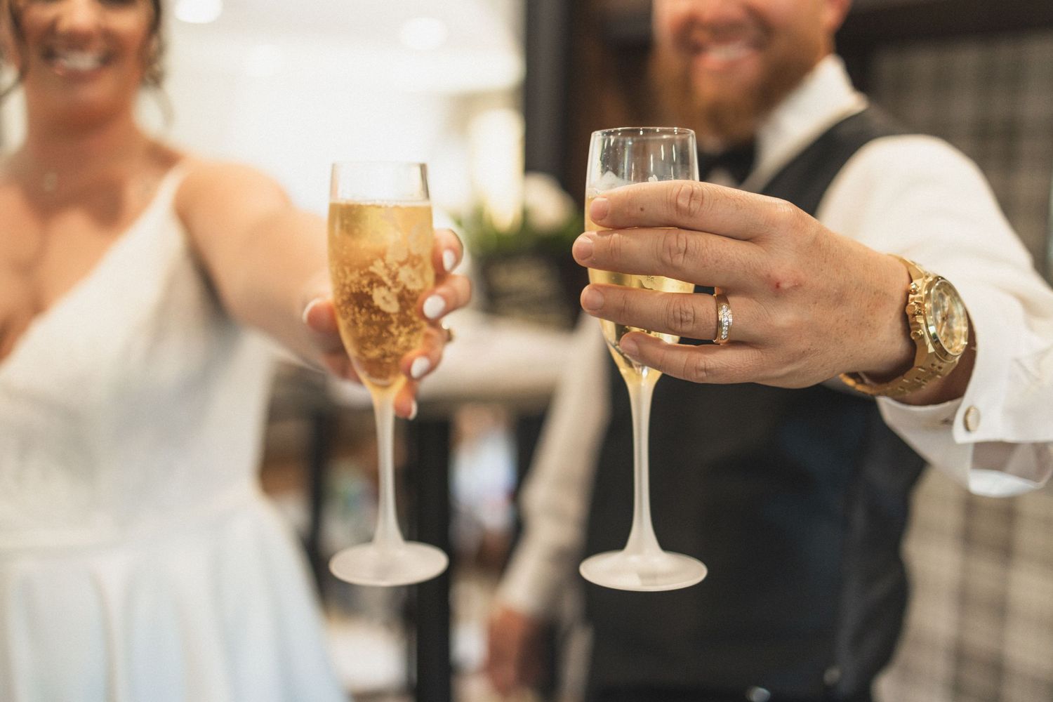 Two champagne flutes clink together in celebration at a wedding reception.