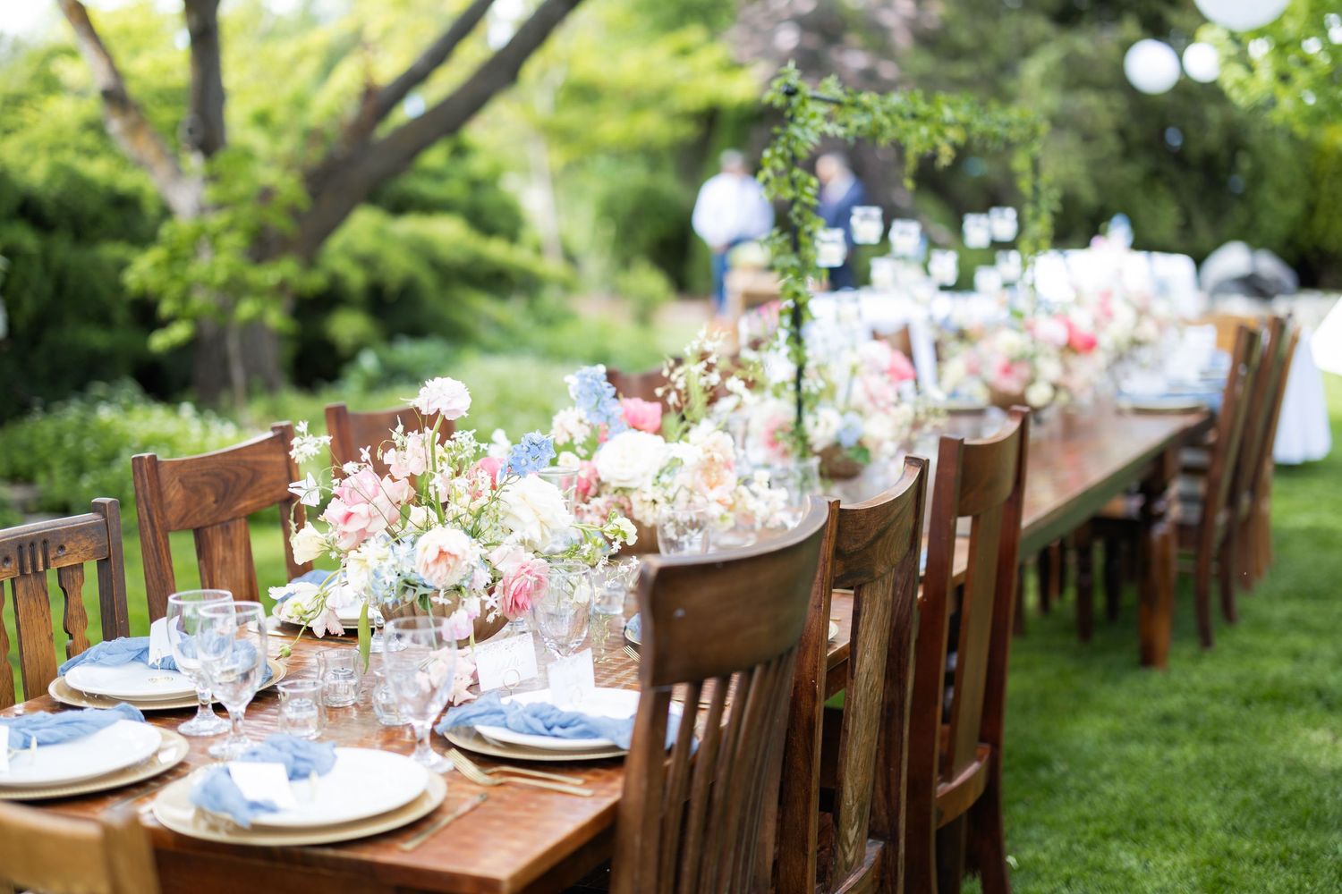 Elegant garden party table settings with delicate floral centerpieces and blue accents.