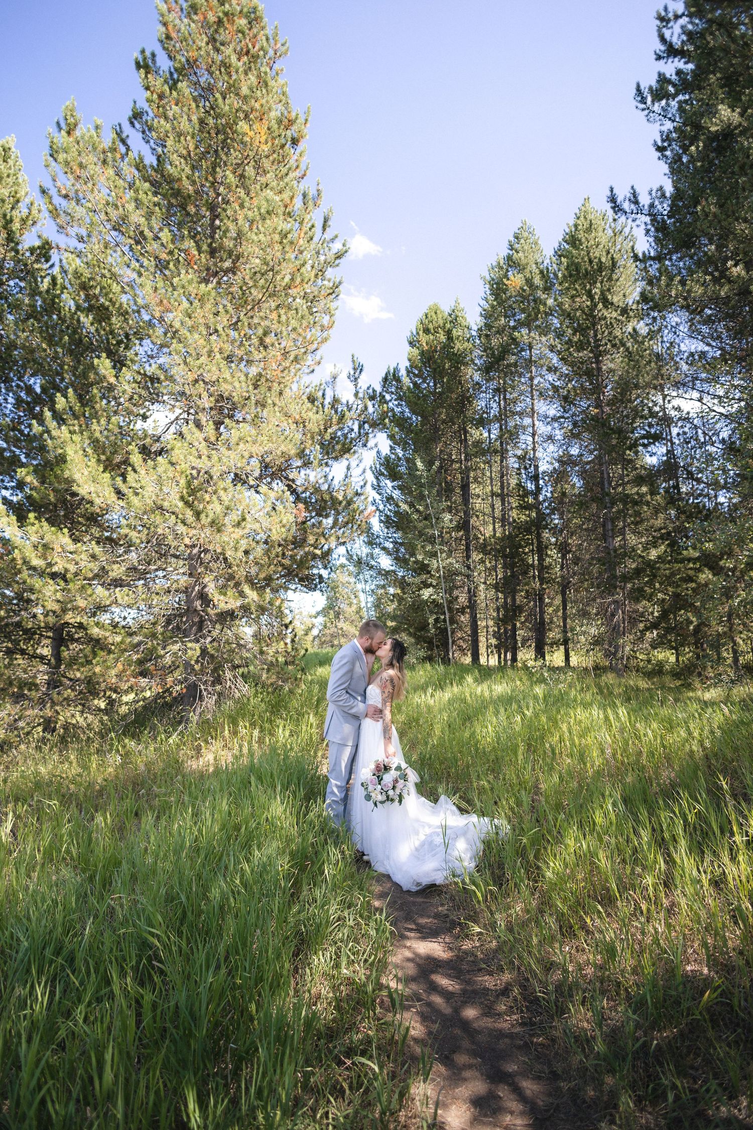 A romantic wedding photoshoot among tall pine trees and grassy meadows.
