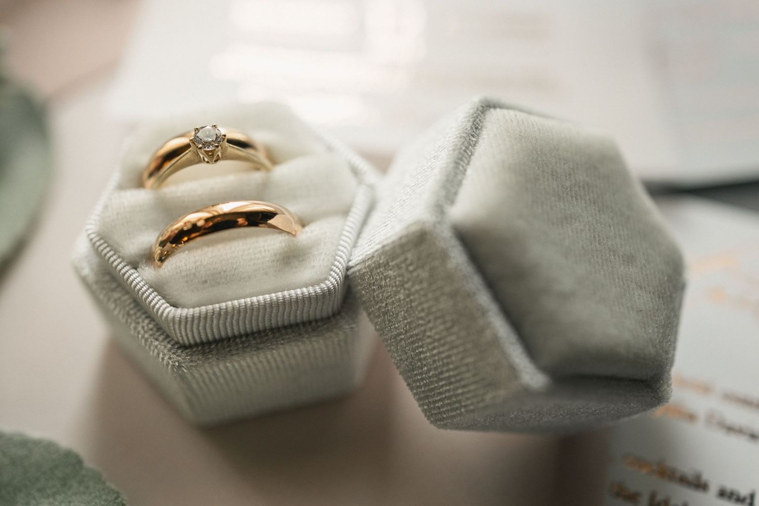 Two gold wedding rings rest in an elegant gray velvet hexagonal ring box.