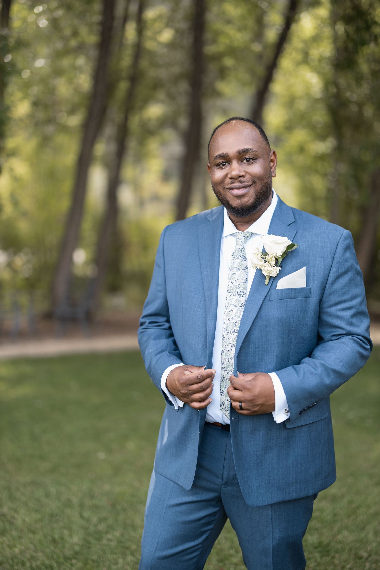 Formal portraits showing details of blue suit and floral tie against natural background.