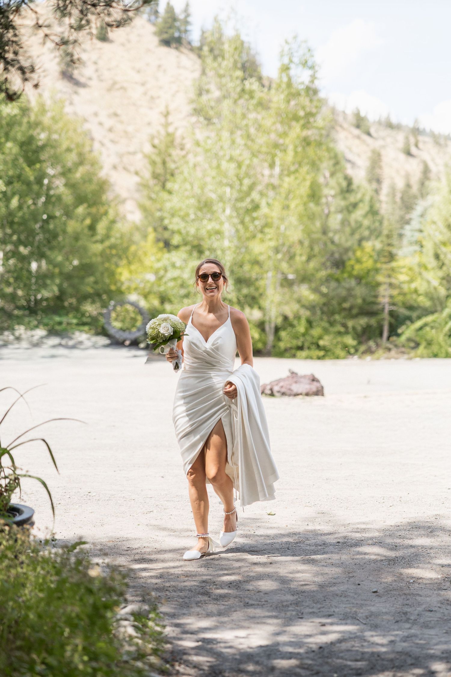 Outdoor bridal photography session on rocky terrain with mountain landscape backdrop.