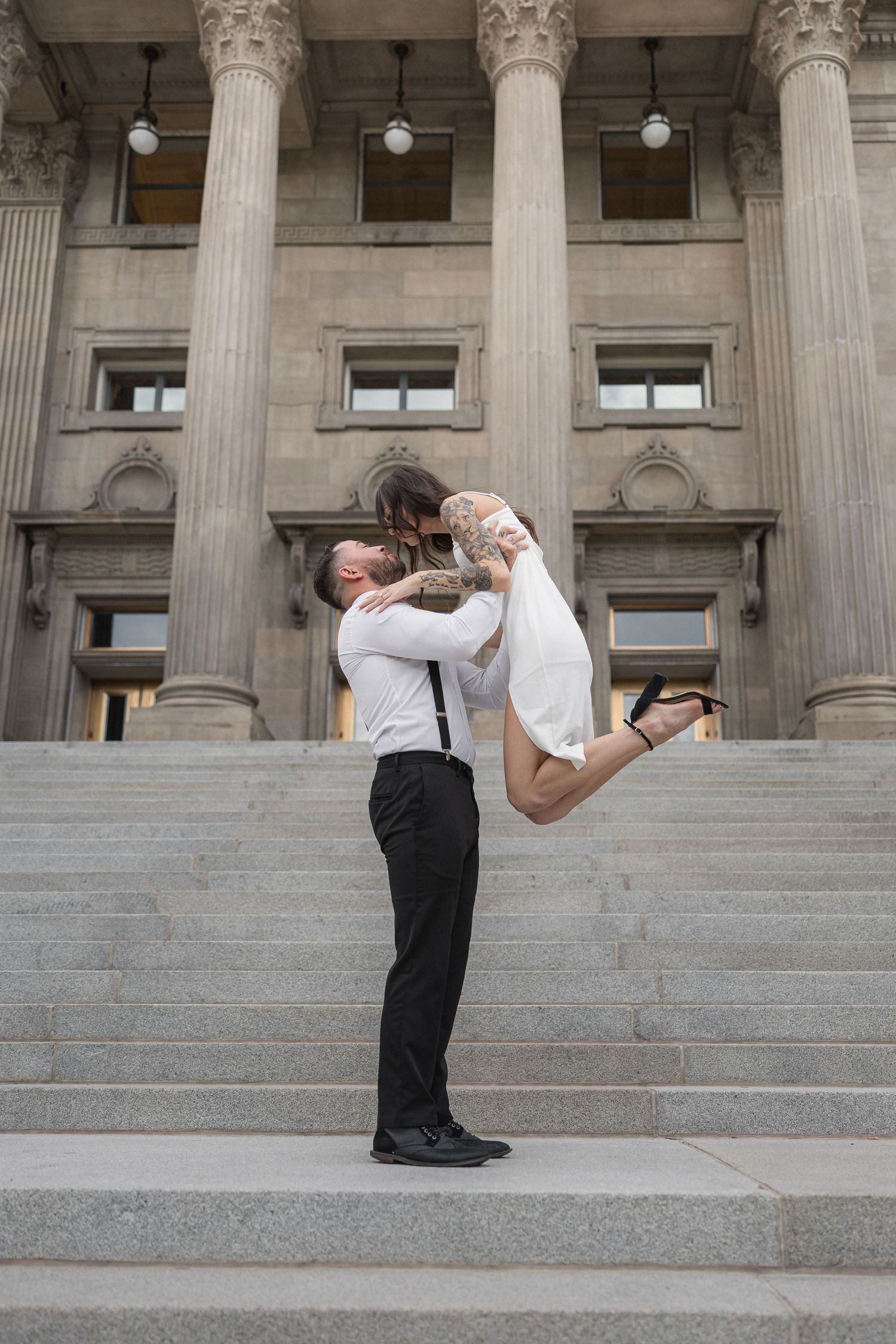 A couple shares a dramatic dance pose on the steps of a classical building with columns.