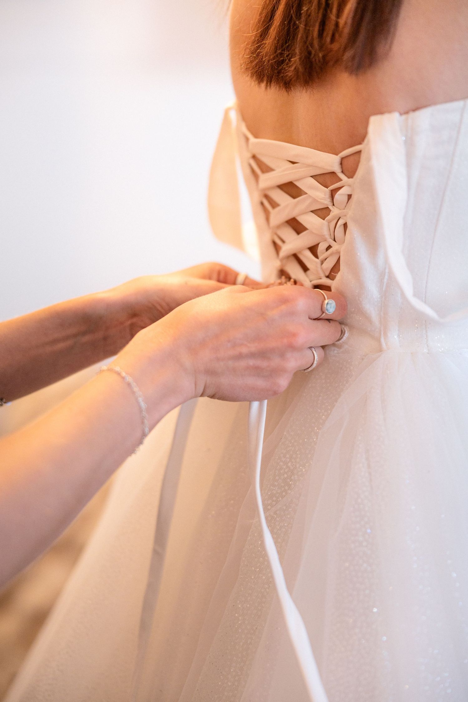 Detail shot of a white wedding dress being laced up in corset style.
