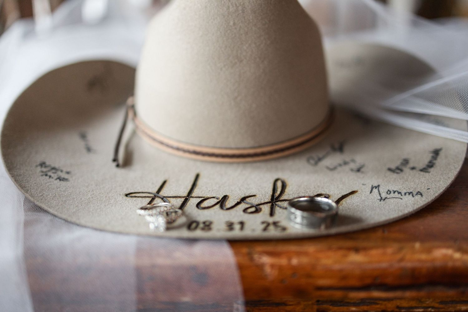 White cowboy hats with handwritten text sit on a wooden surface.