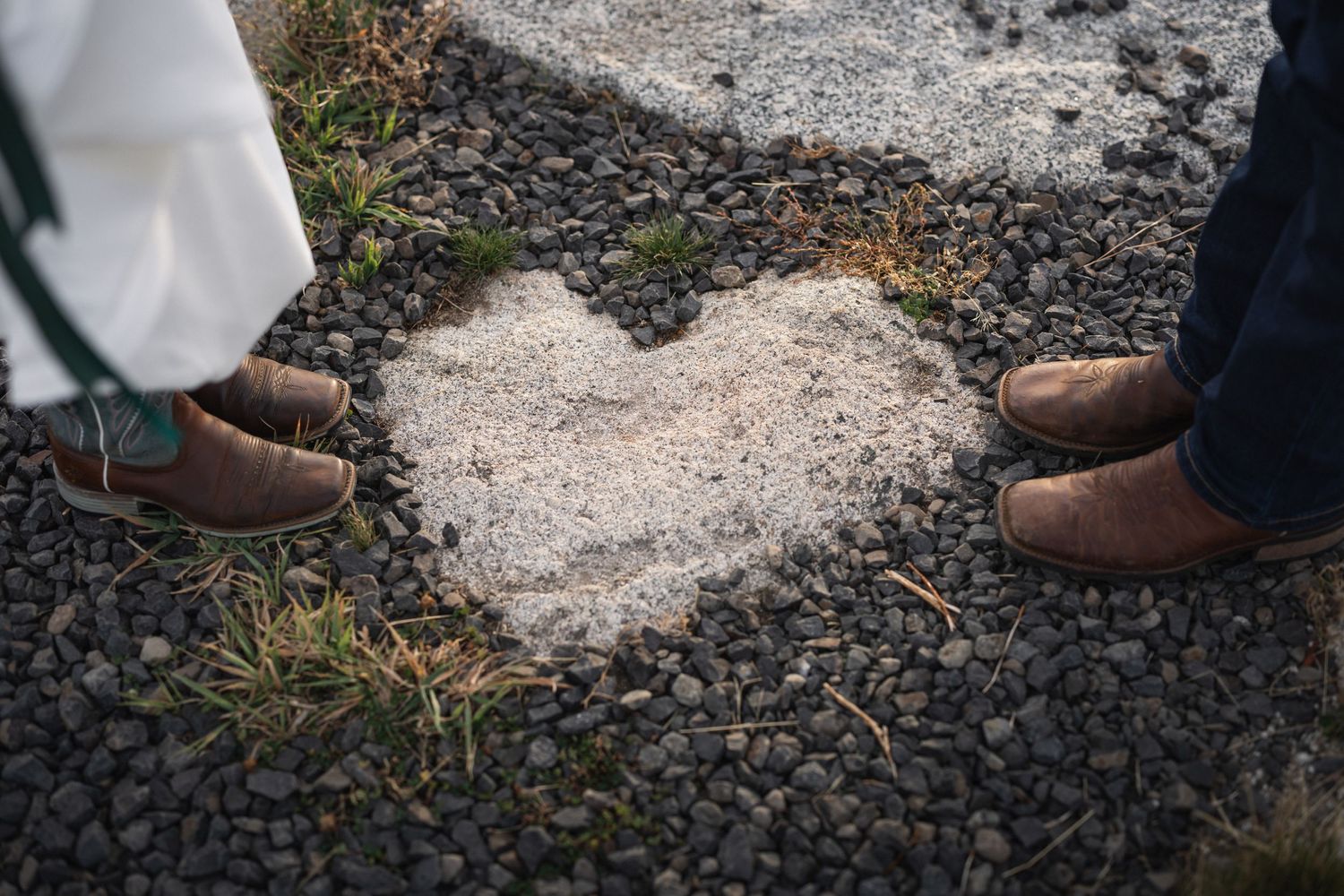 Creative wedding photo showing brown boots forming heart shape on rocky ground.