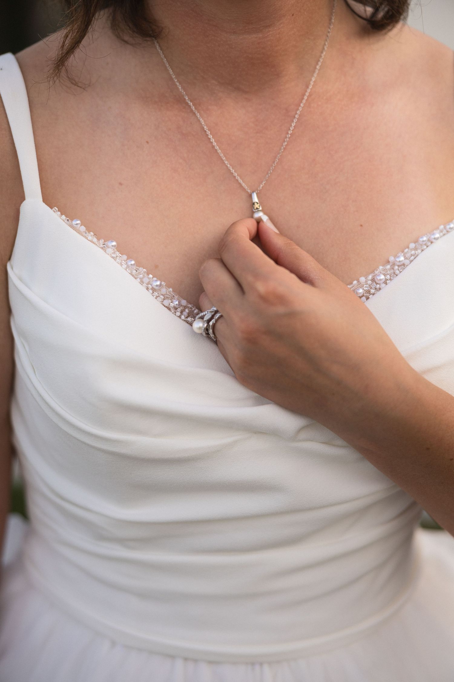 Close-up of a delicate lace wedding dress neckline with a silver necklace.