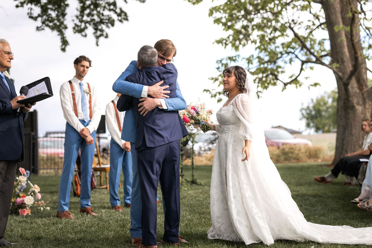 Emotional embrace shared during outdoor wedding ceremony with guests looking on.
