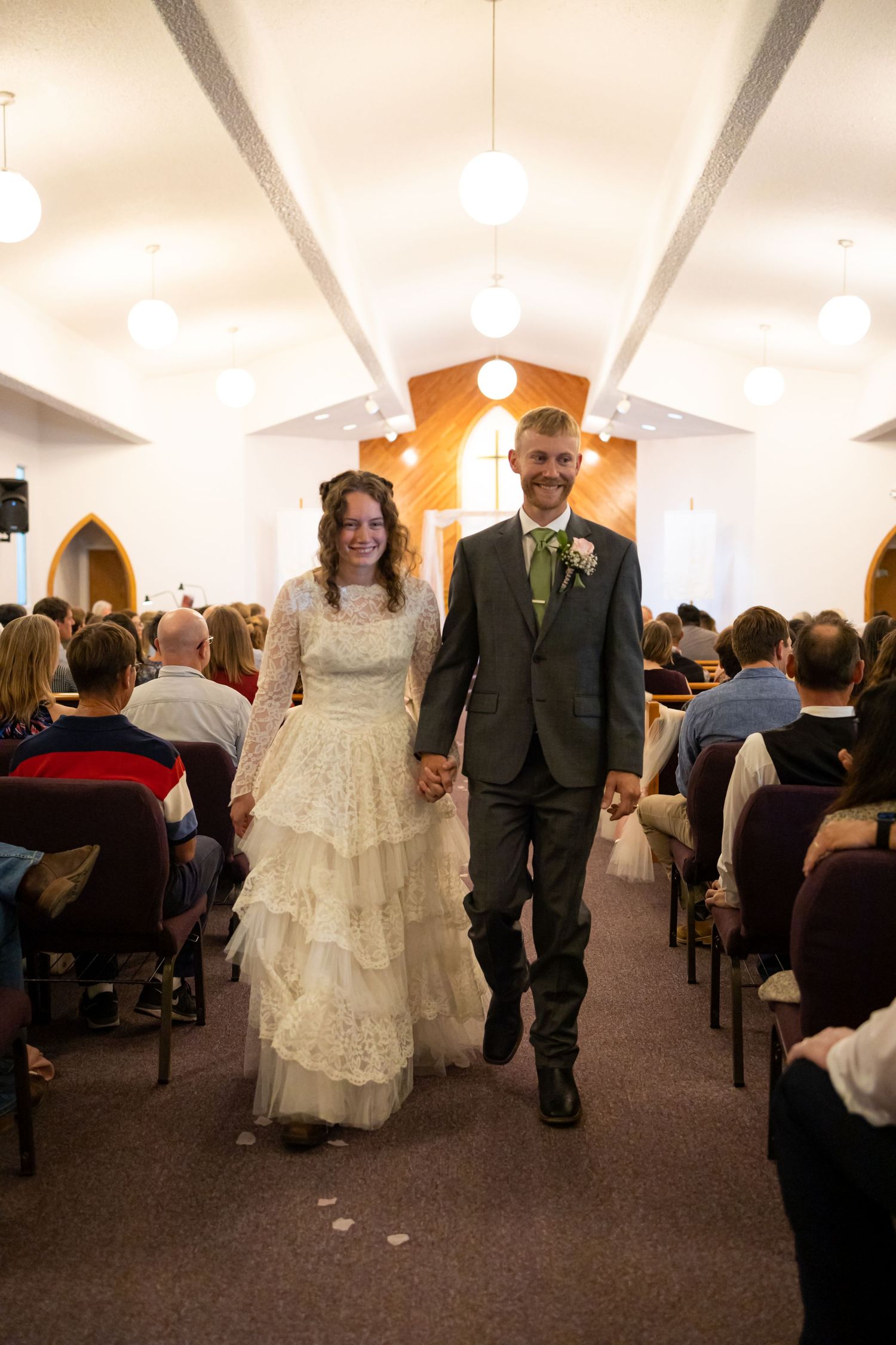 Couple walking down church aisle after wedding ceremony with guests seated.