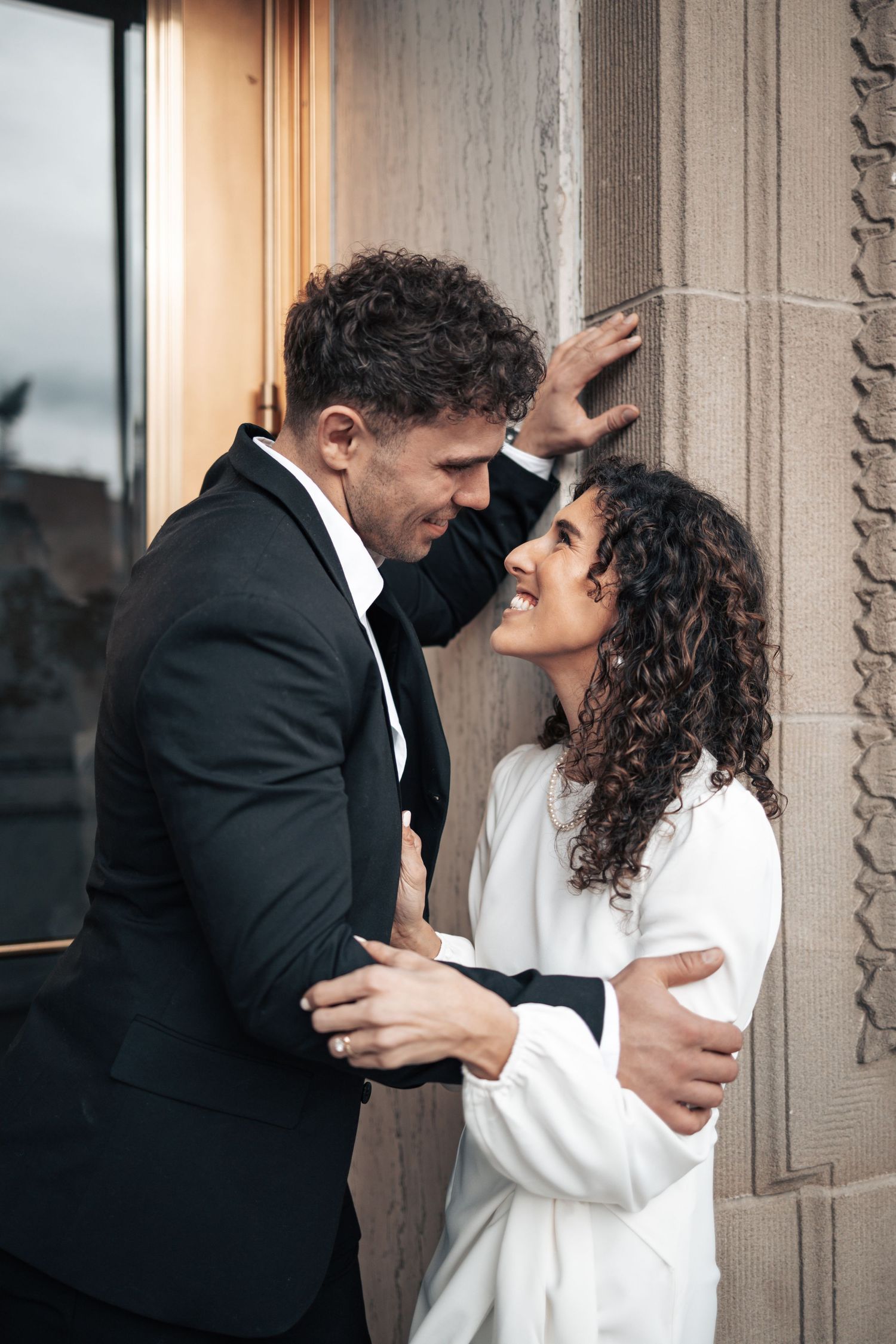 Close-up of couple sharing tender moment against stone building exterior.