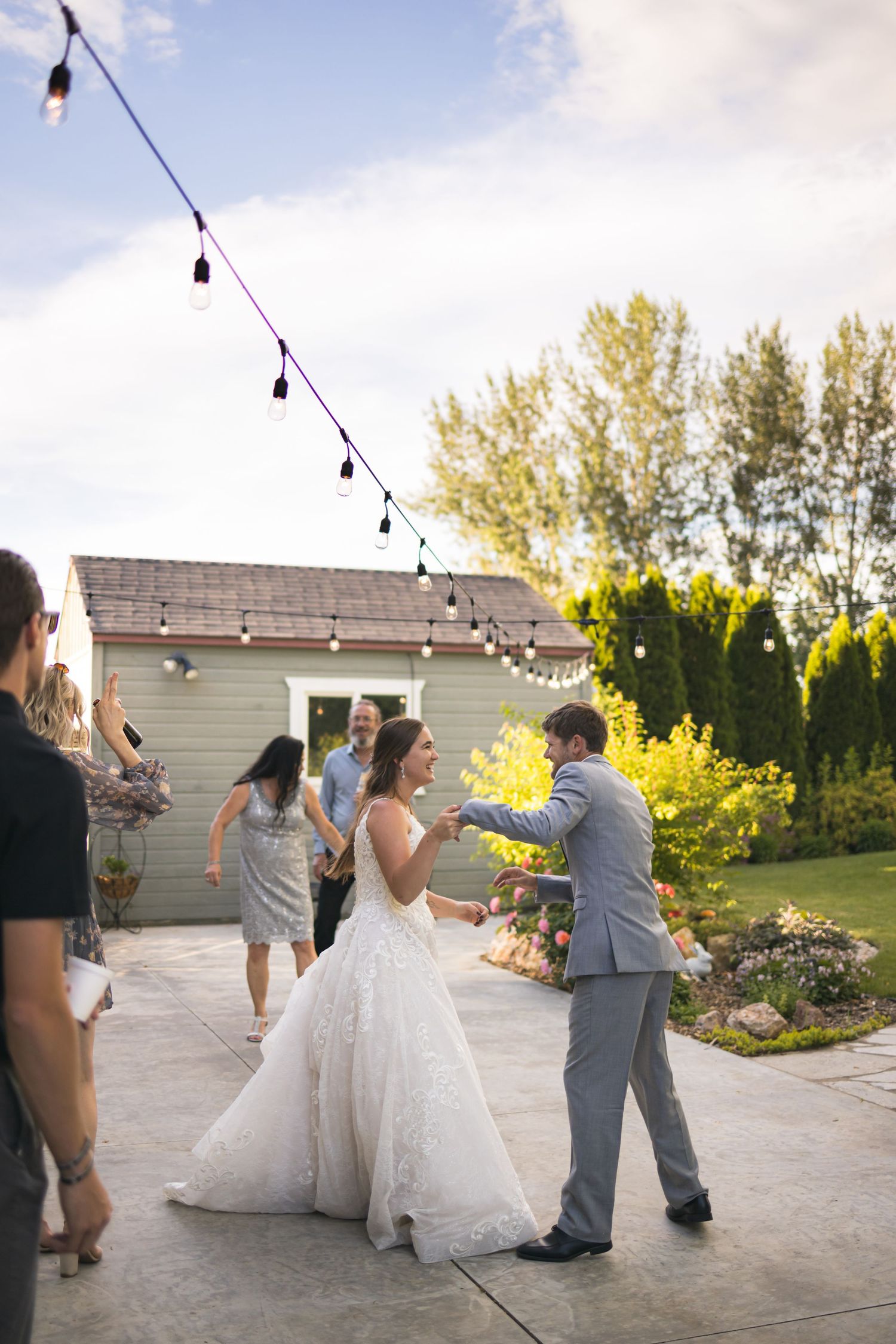 A wedding celebration on an outdoor patio with string lights and garden landscaping.