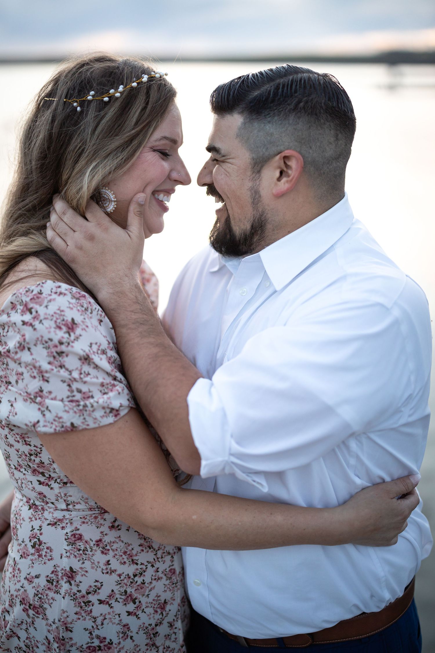 Romantic couple moment captured against sunset water backdrop.