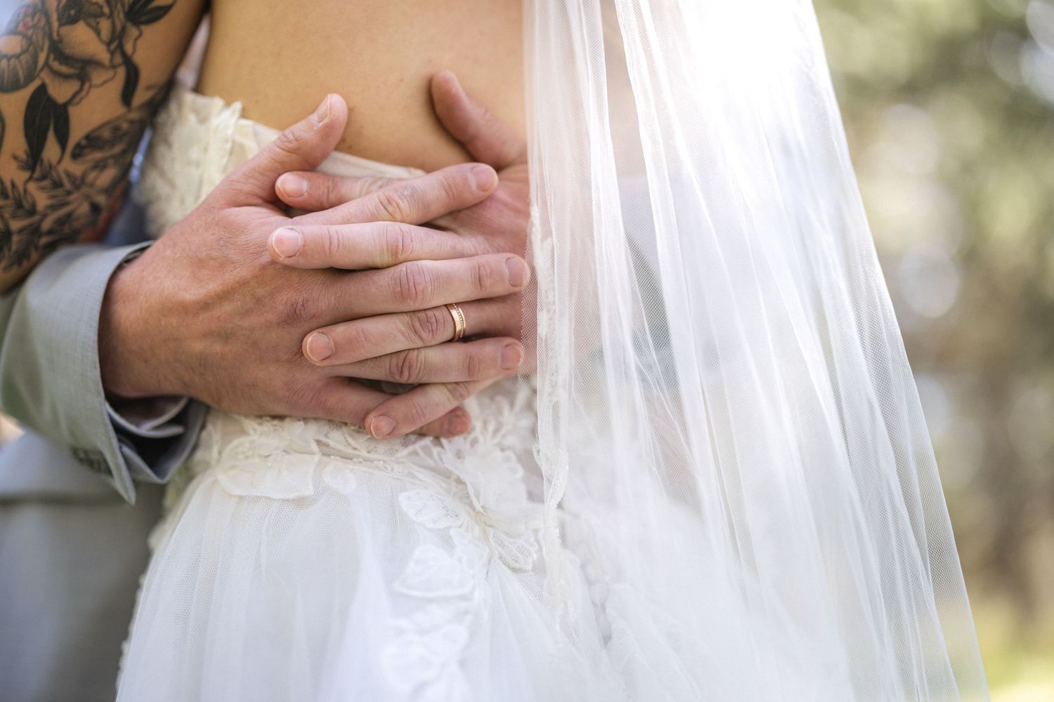 Detail shot of hands embracing with wedding rings visible.