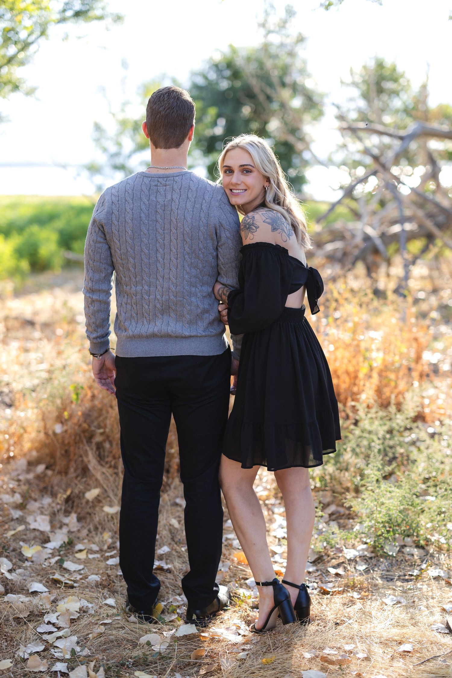 Romantic couple pose together on rugged terrain during golden hour.