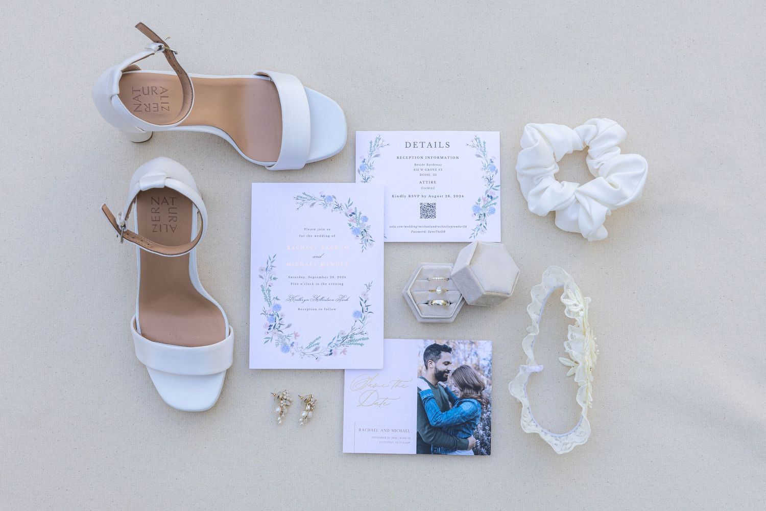 Wedding day details including invitations, shoes, and lace accessories arranged on white surface.