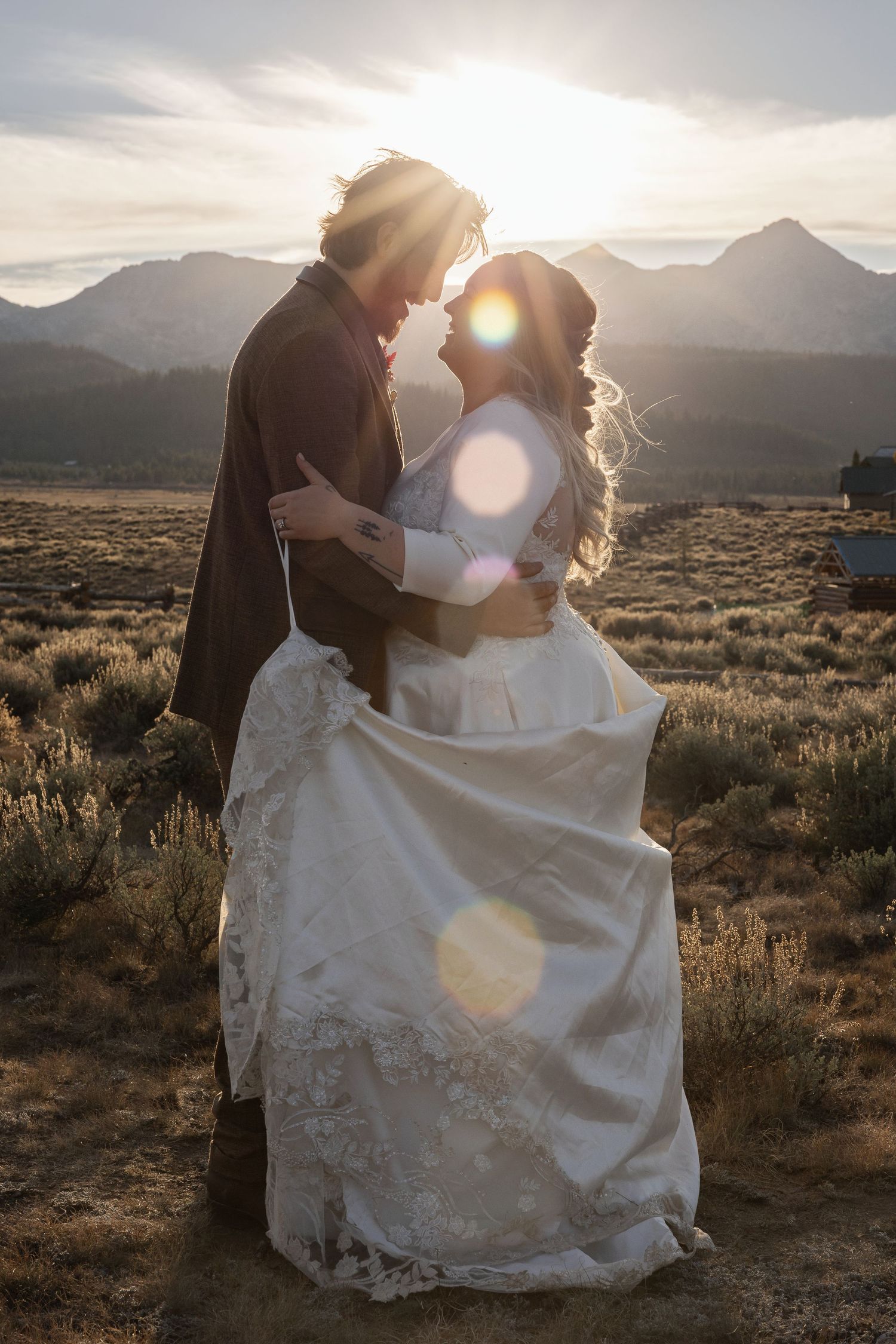 Romantic sunset wedding portraits in desert landscape with mountain silhouettes.