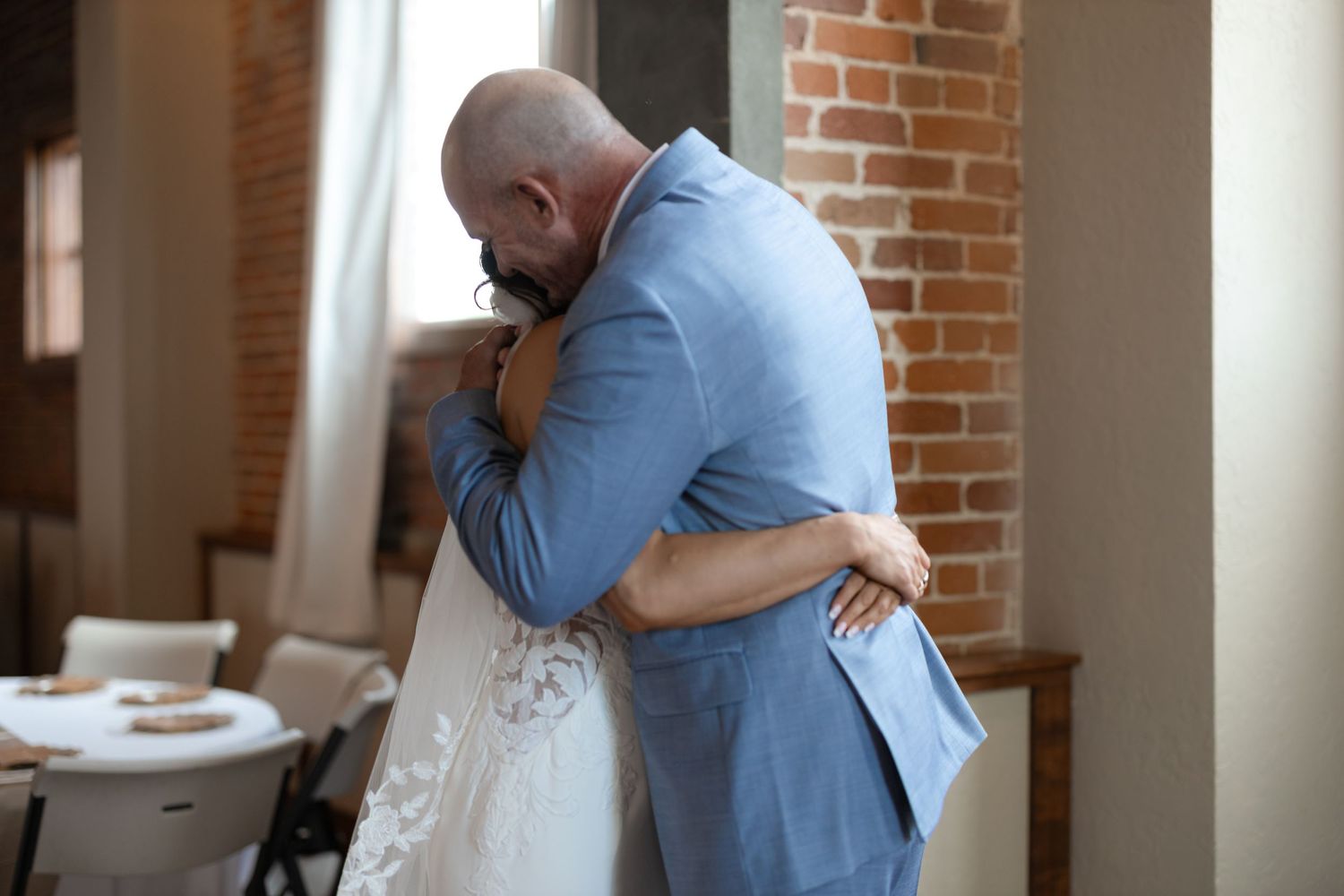 Tender embrace between newlyweds during first look in rustic venue.