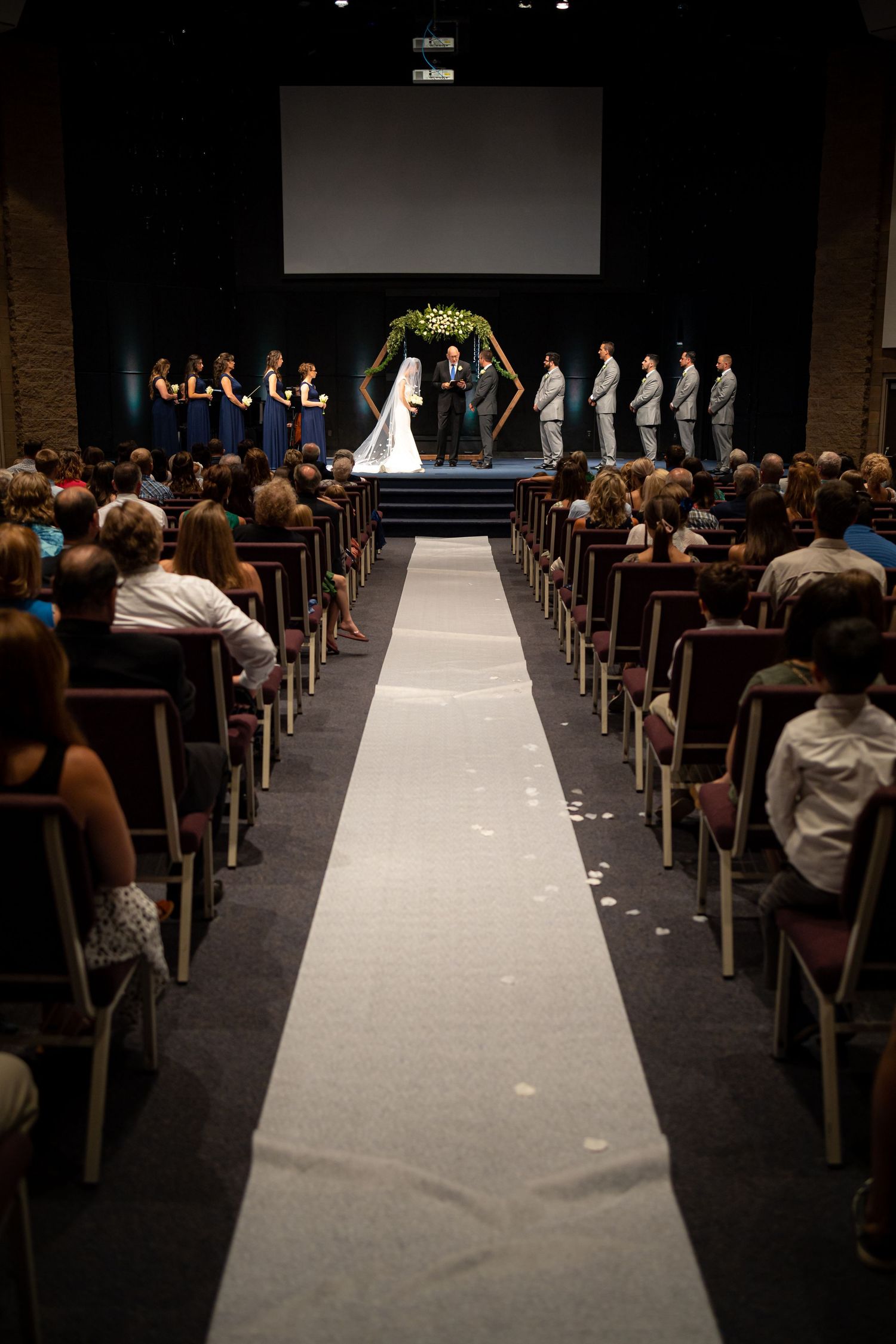 Long white aisle runner leads to altar in modern wedding ceremony venue.