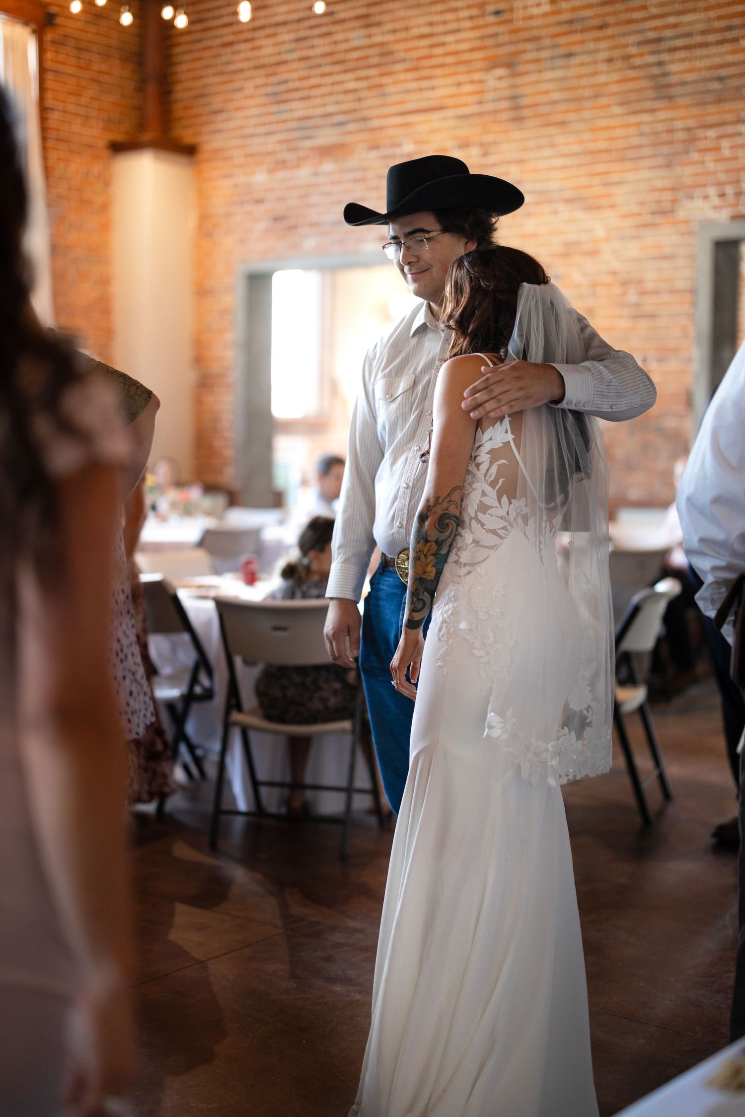 Couple dancing at wedding reception in rustic brick venue with string lights.