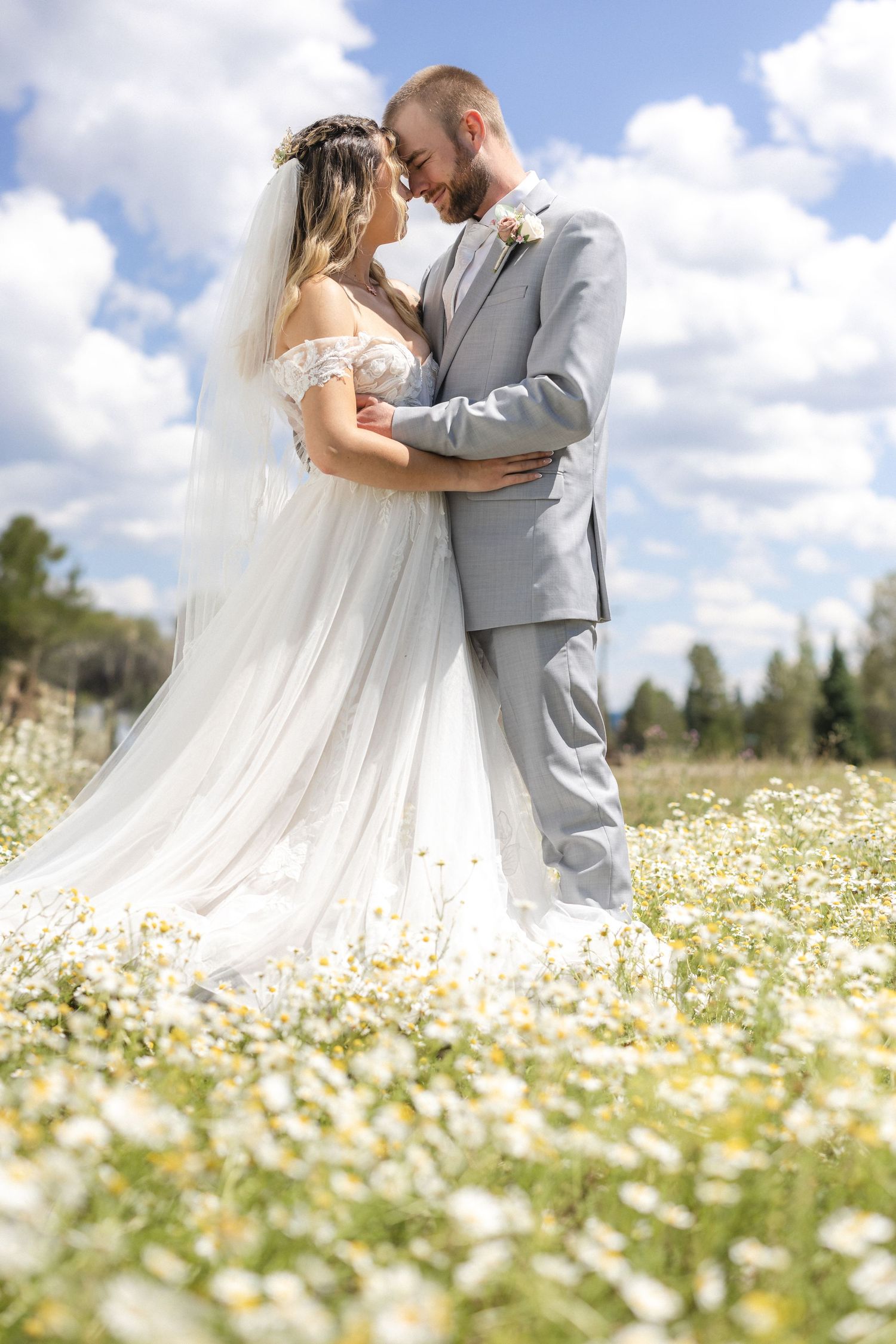 A romantic wedding portrait of a couple embracing in a field of wildflowers.