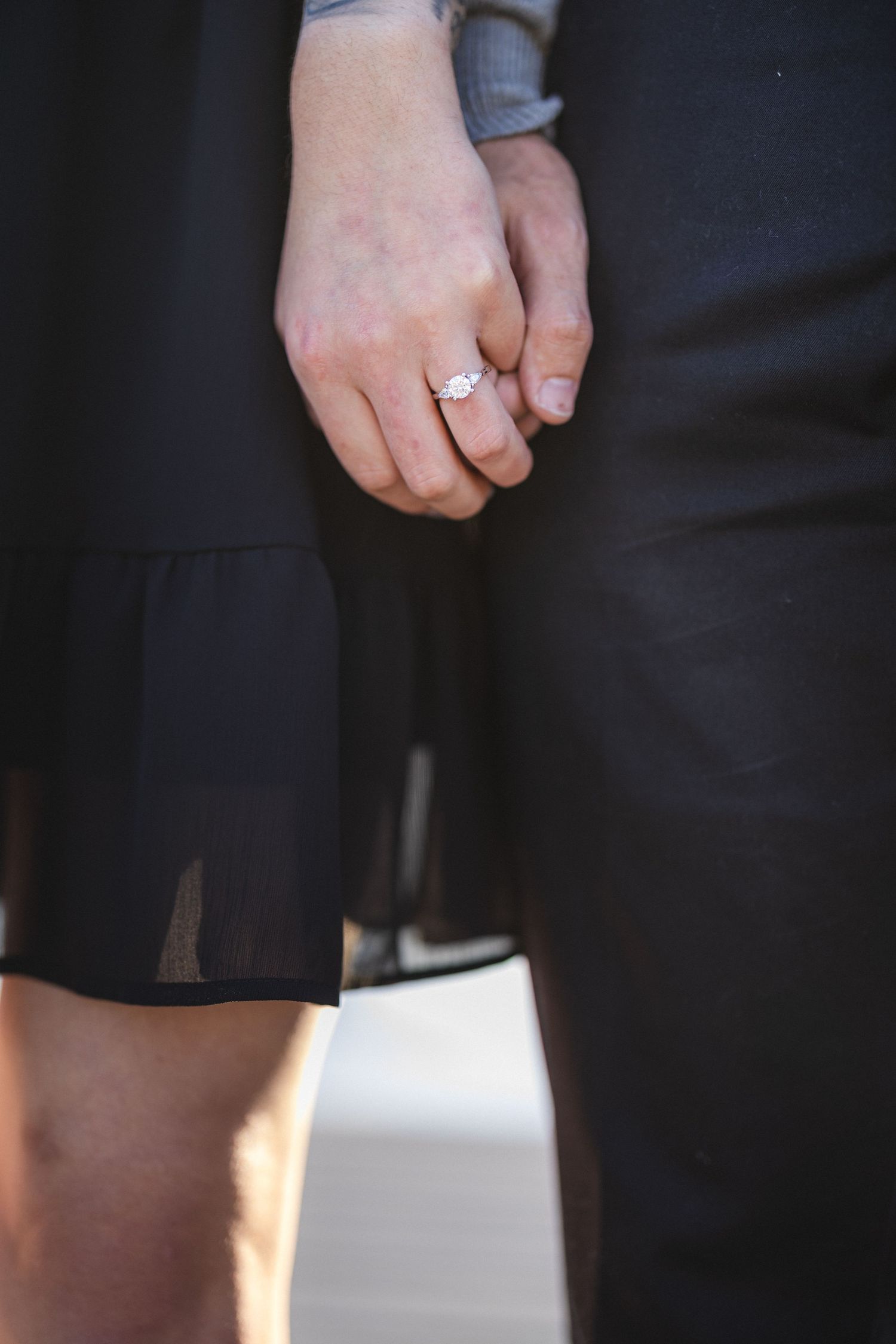Close-up of hands holding together with an engagement ring visible.