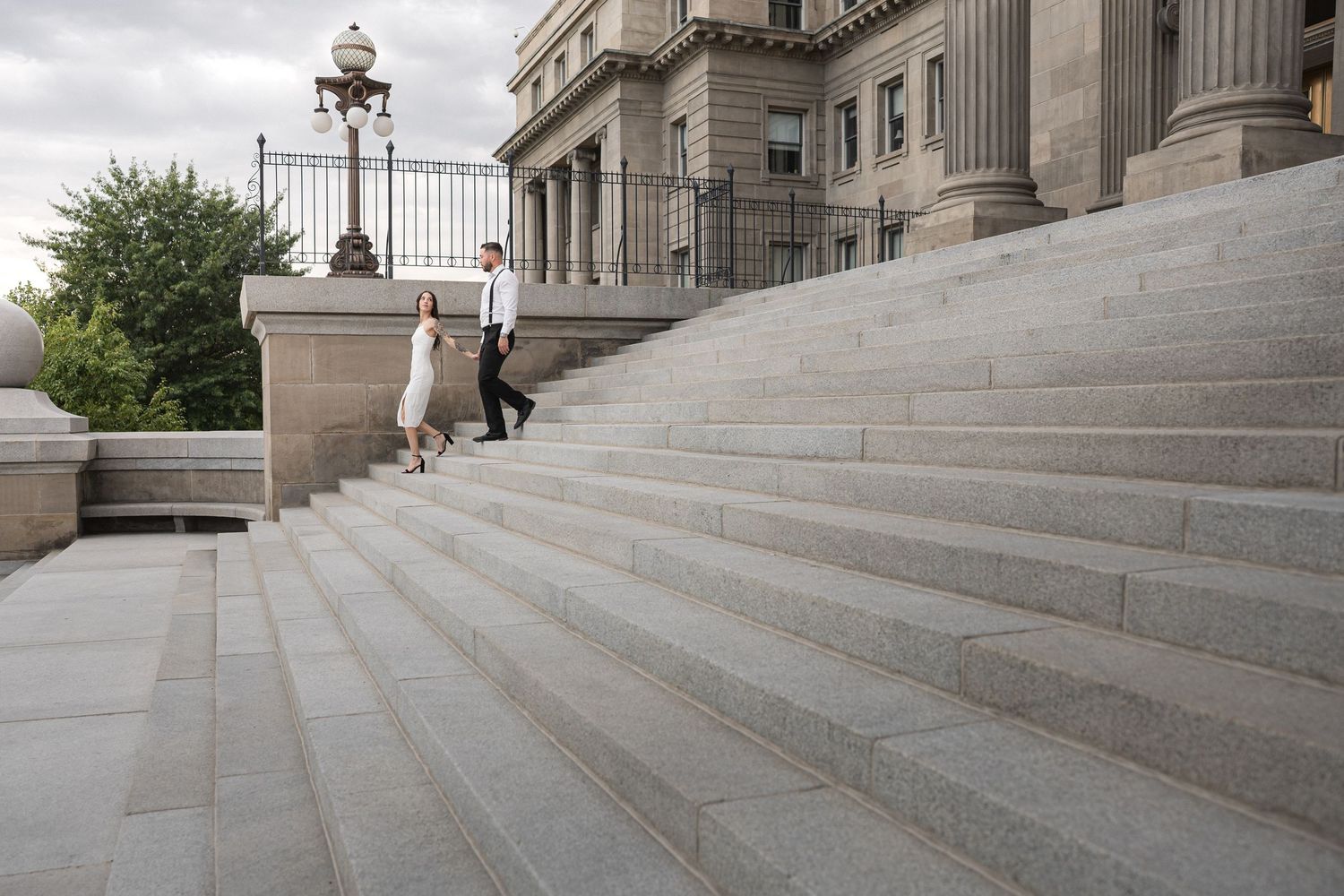 A skateboarder performs a trick sequence down concrete stairs at an urban location.