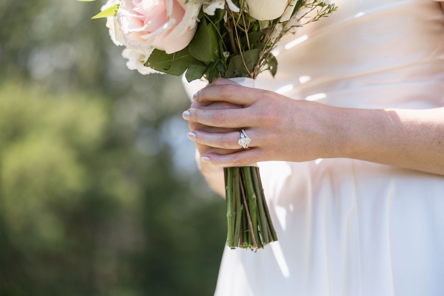 Close-up of a delicate pink and white bridal bouquet with roses and greenery.