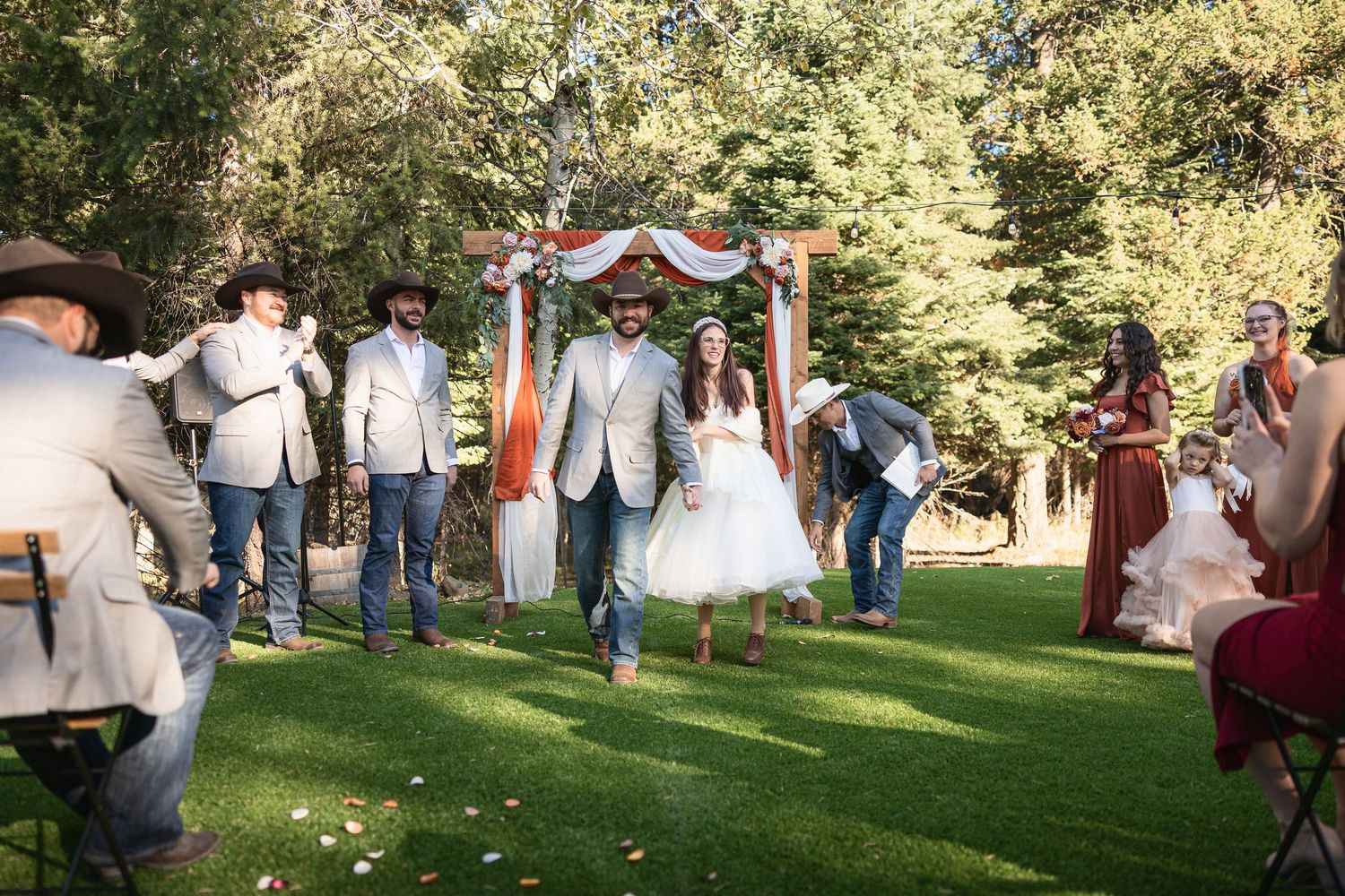 Wedding guests gathered on grassy lawn during outdoor autumn ceremony.
