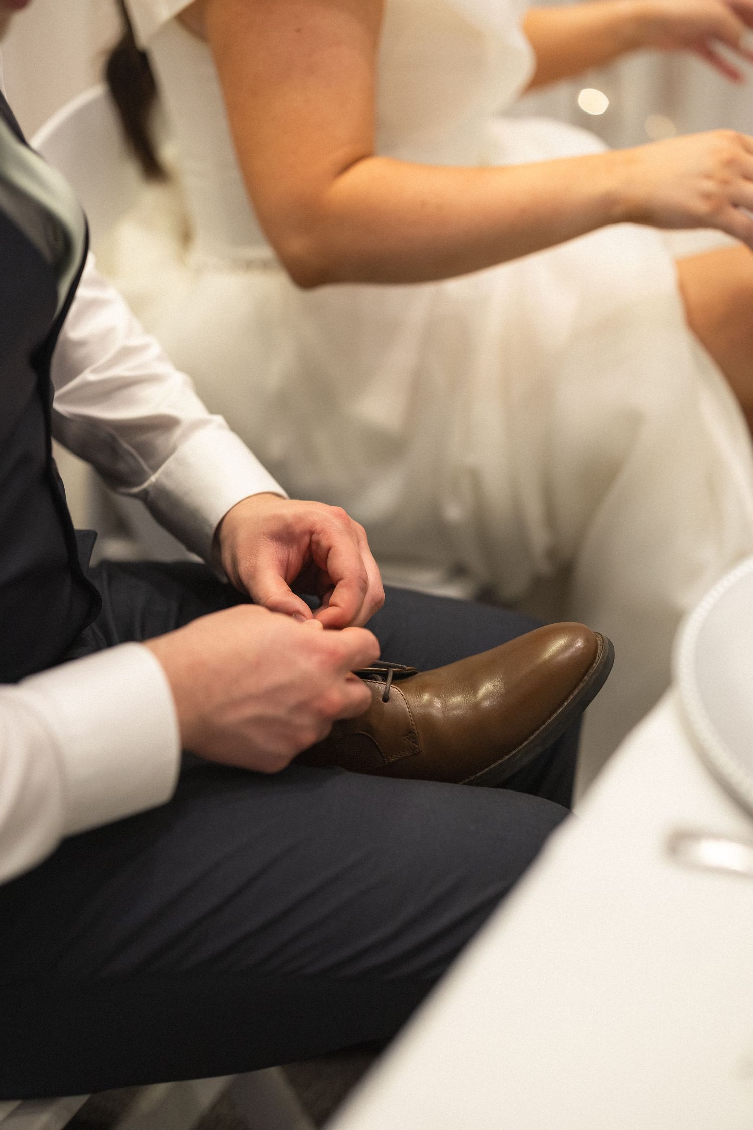 Close-up shot of formal brown dress shoes being adjusted during a wedding.