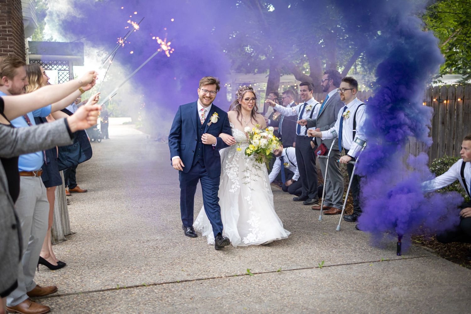 Wedding celebration with purple smoke effects creating dramatic atmosphere outdoors.