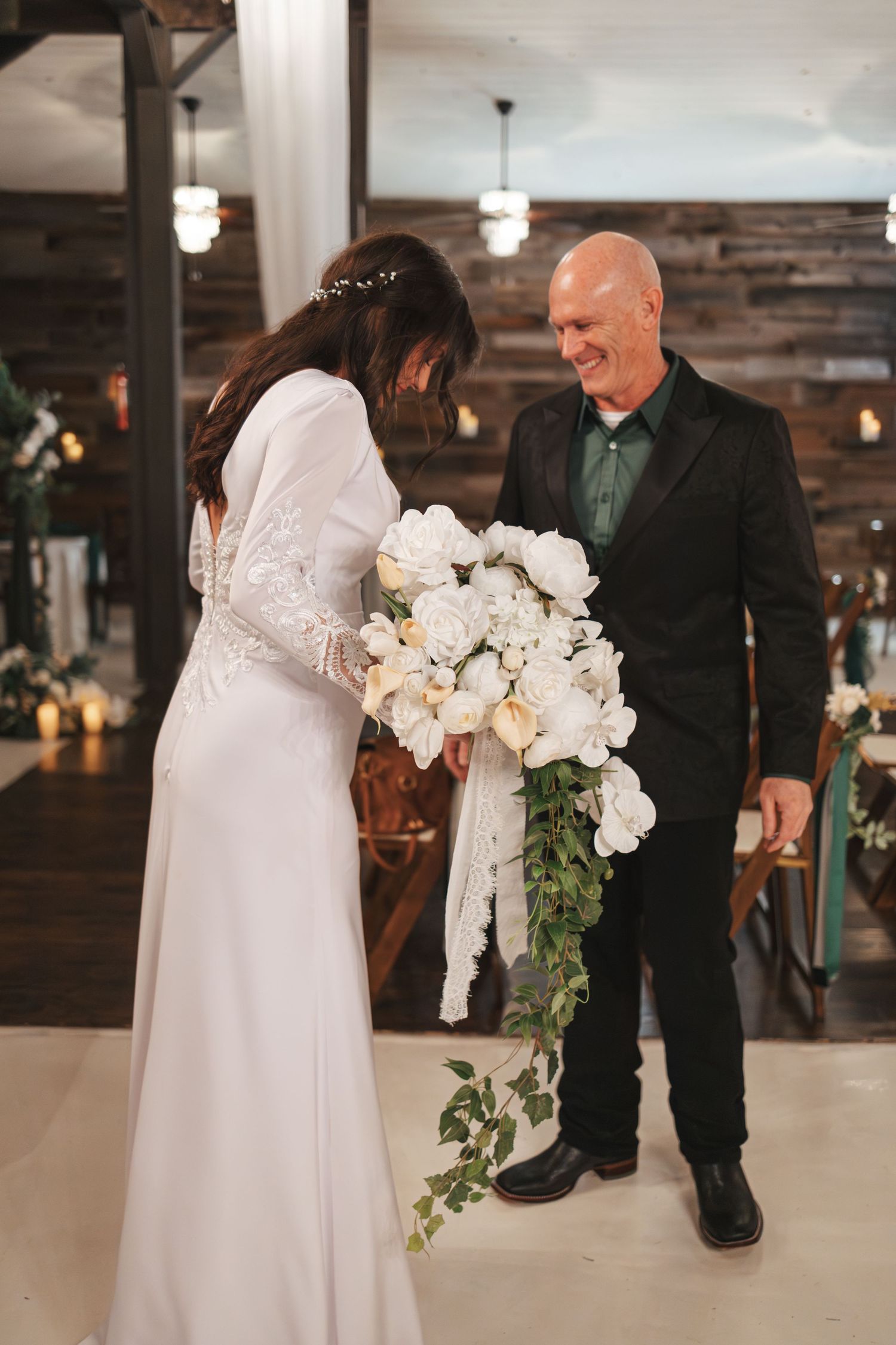 Wedding moment captured in rustic indoor venue with wooden walls and warm lighting.