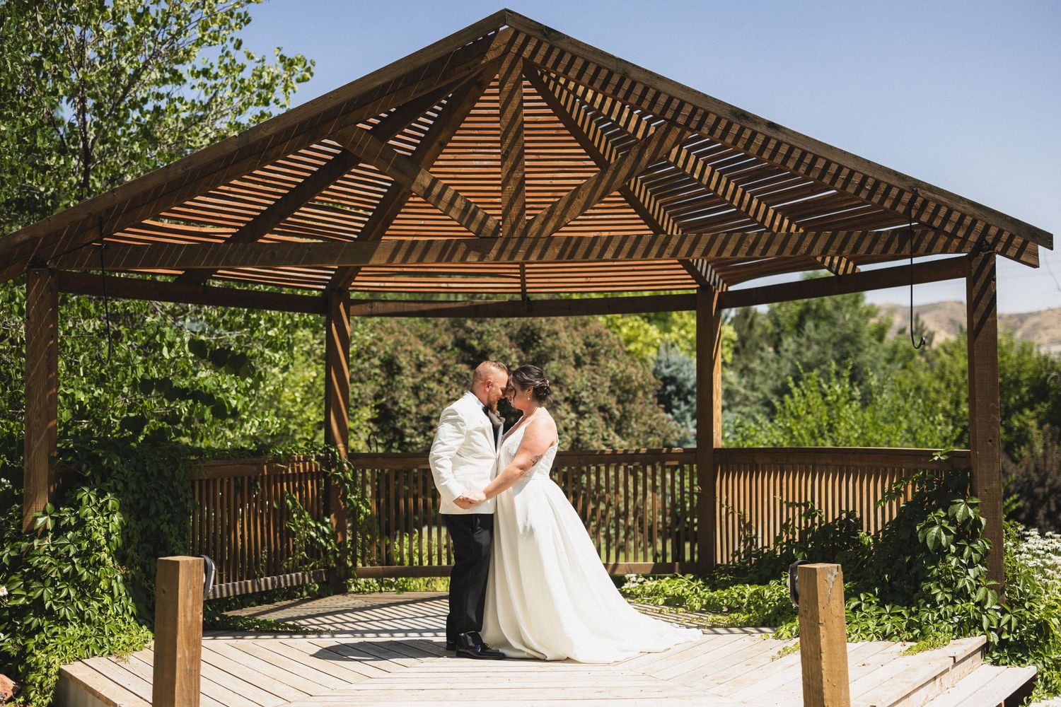 Romantic embrace under a geometric wooden pavilion during wedding portraits.