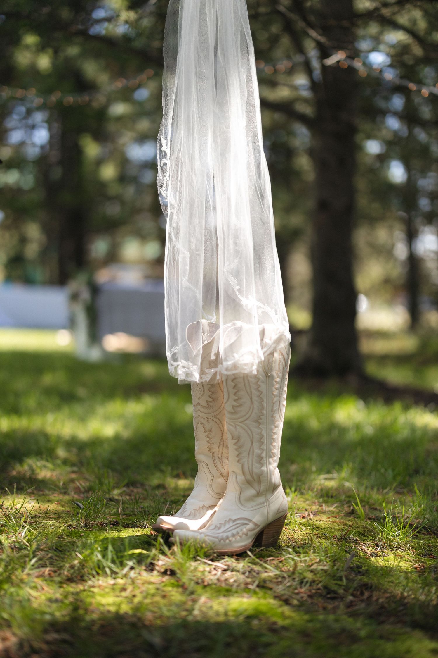 Lace wedding boots with flowing veil against forest backdrop.