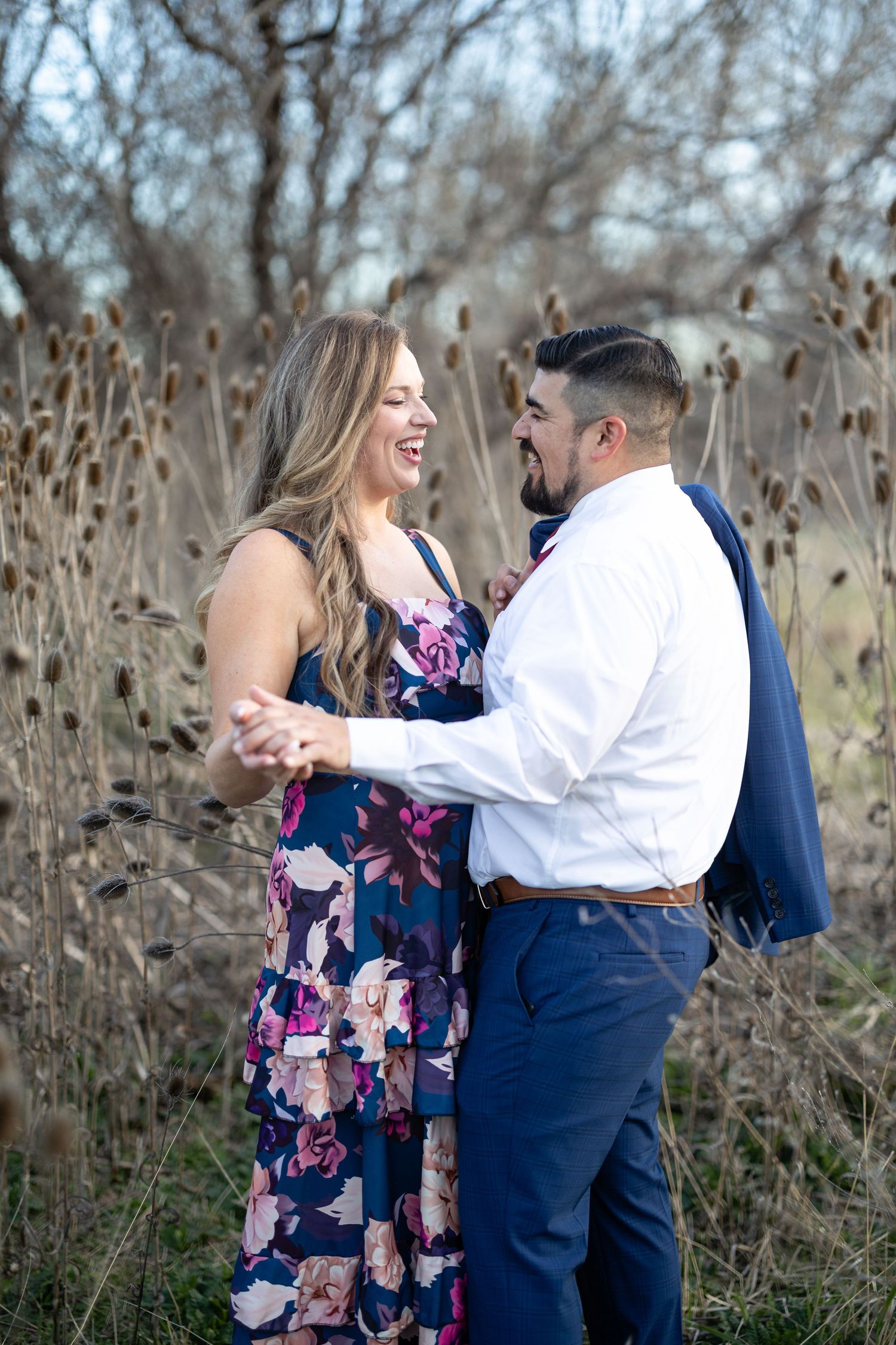 A couple embraces and laughs together during their engagement photo session in nature.