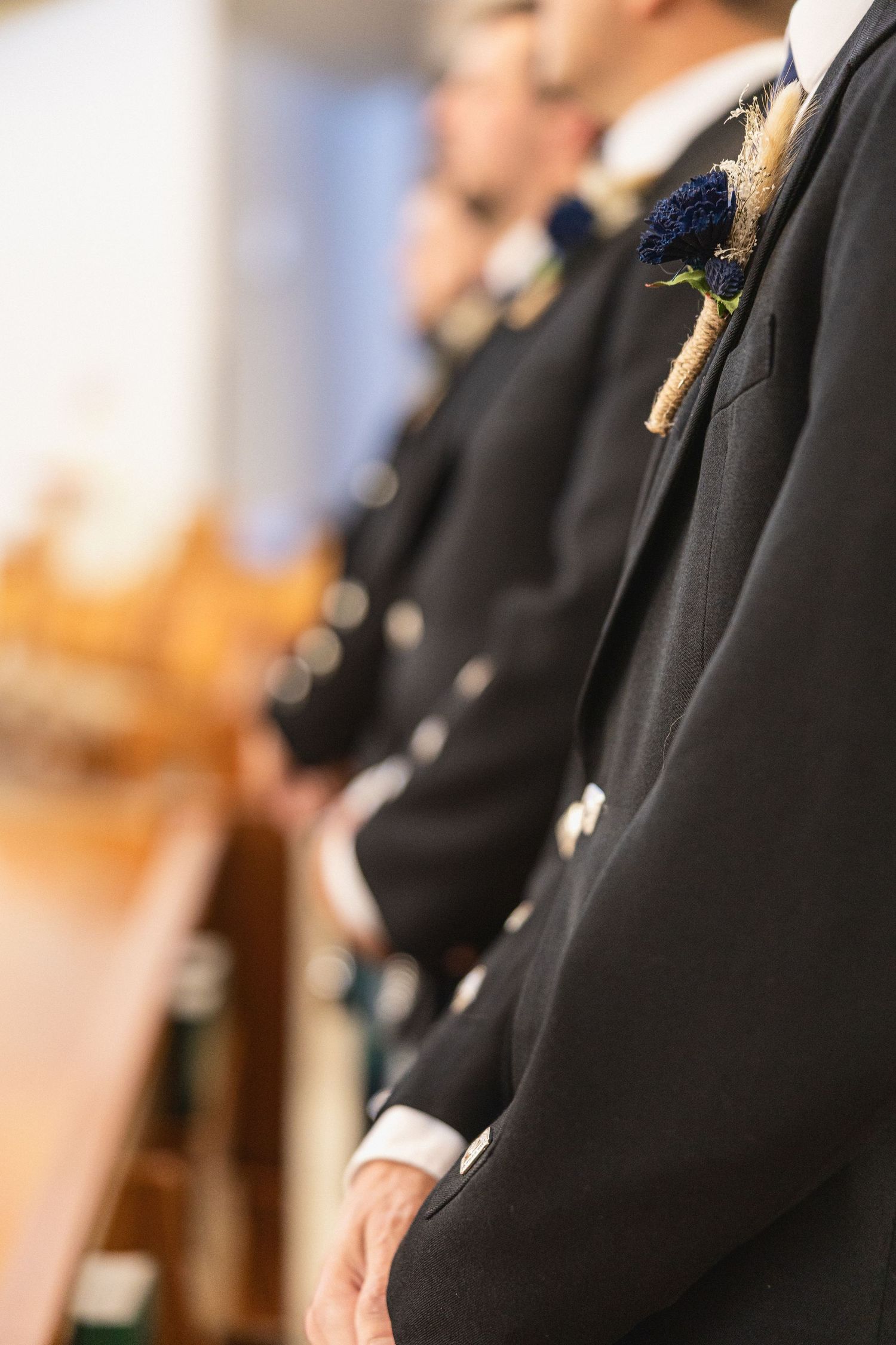 Close-up of formal black suit with navy blue thistle boutonniere.