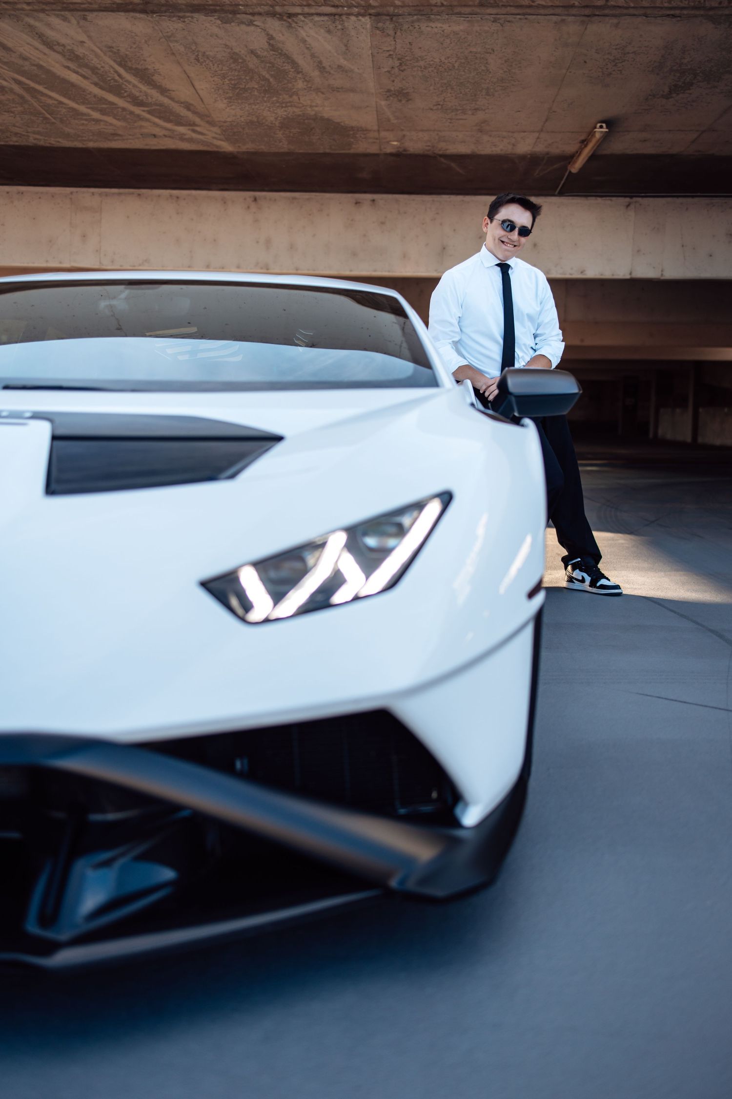 White Lamborghini photographed from dynamic low angle in concrete parking structure.