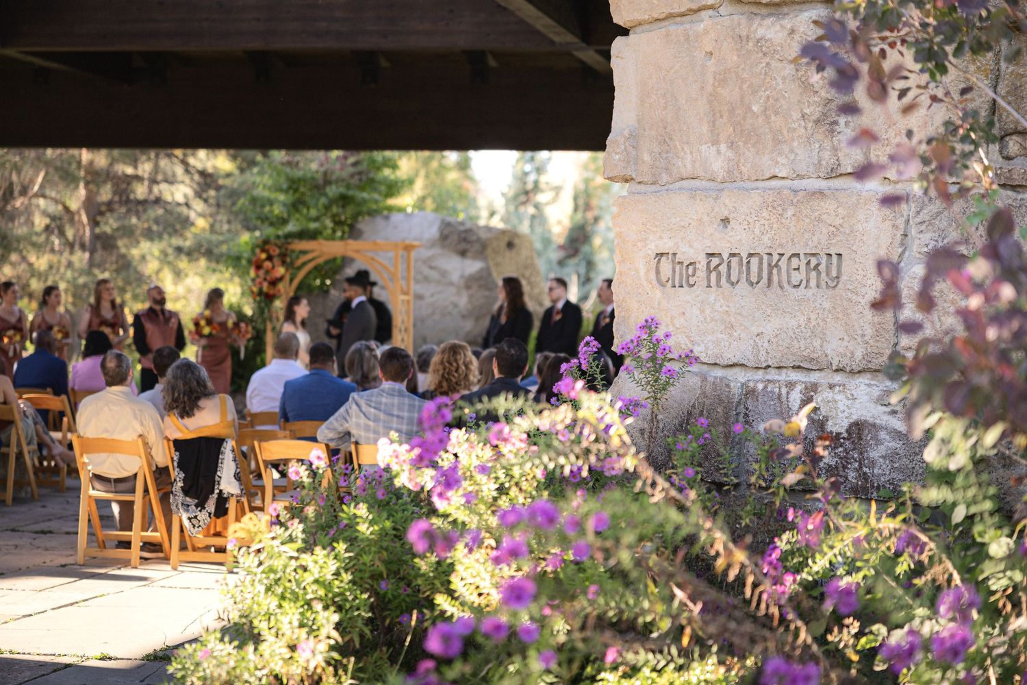 Outdoor wedding venue with stone pathway and purple flowers in natural garden setting.