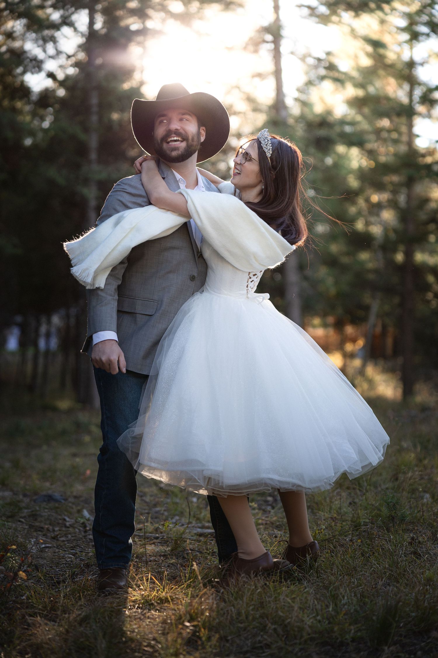Playful wedding dance poses captured in a sun-dappled forest setting.